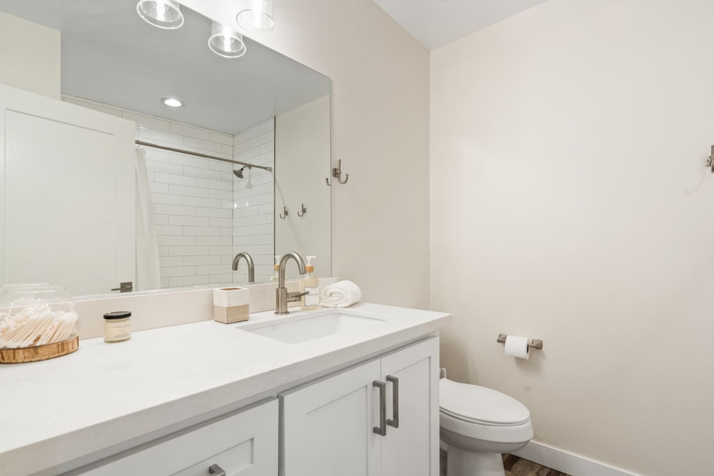 Guest bathroom with vanity storage, bright mirror lighting, setup for daily routines. Backup towels are stored under vanity.