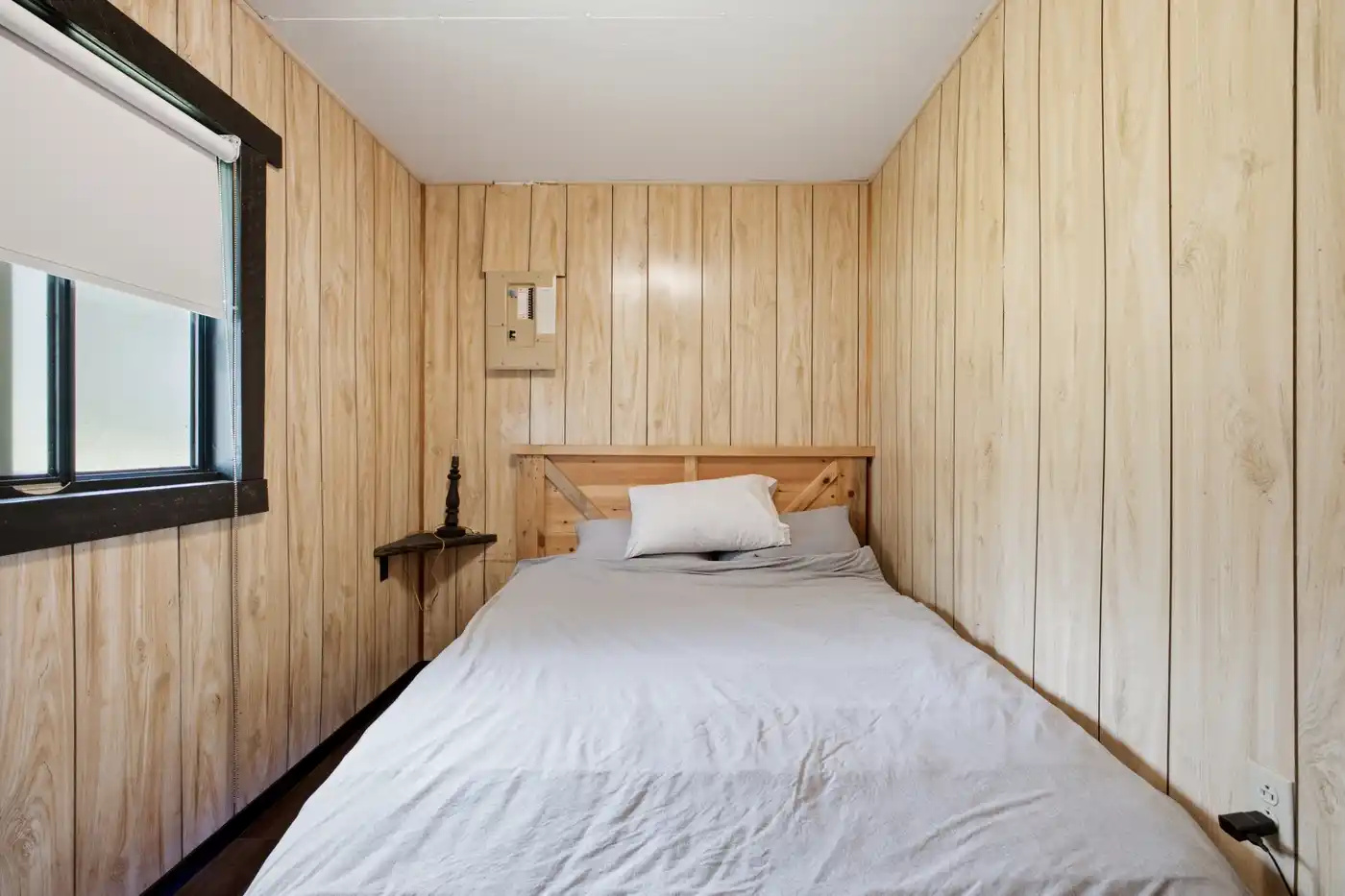 Cozy bedroom with simple wood-paneled walls