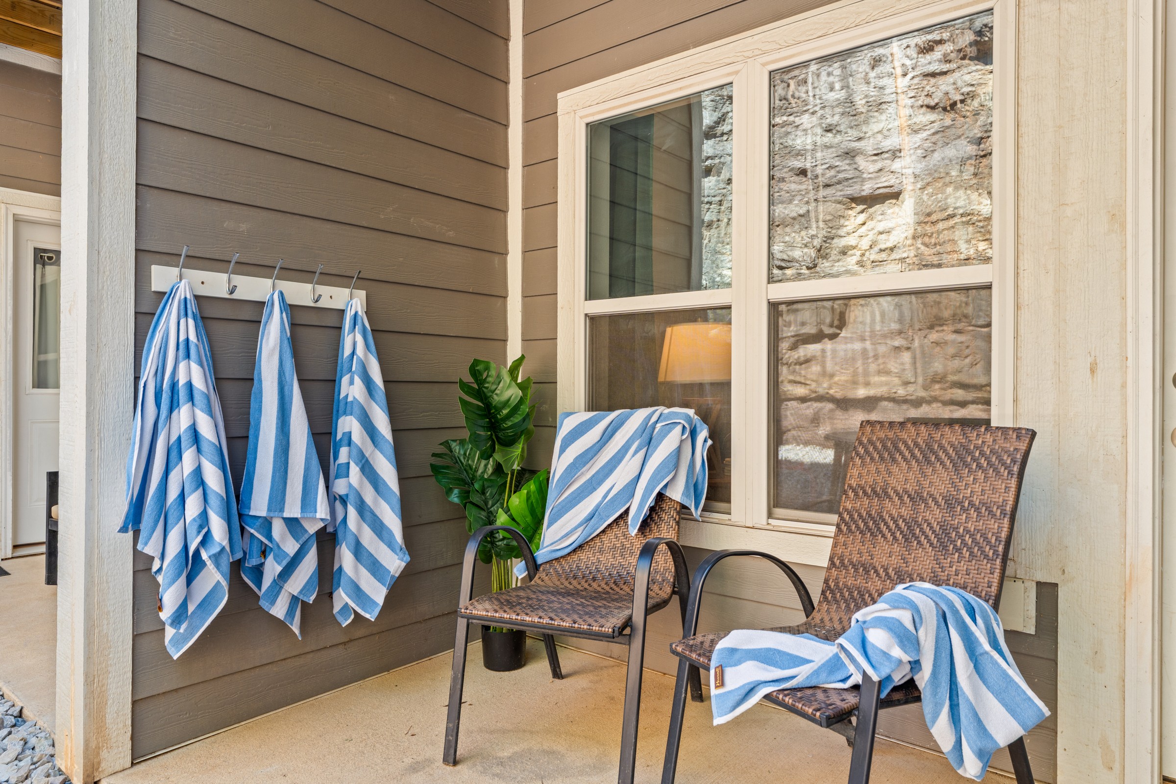 Covered patio with towel hooks and two chairs by the rock bluff. Hang your wet towels here after the pool and sit a while.