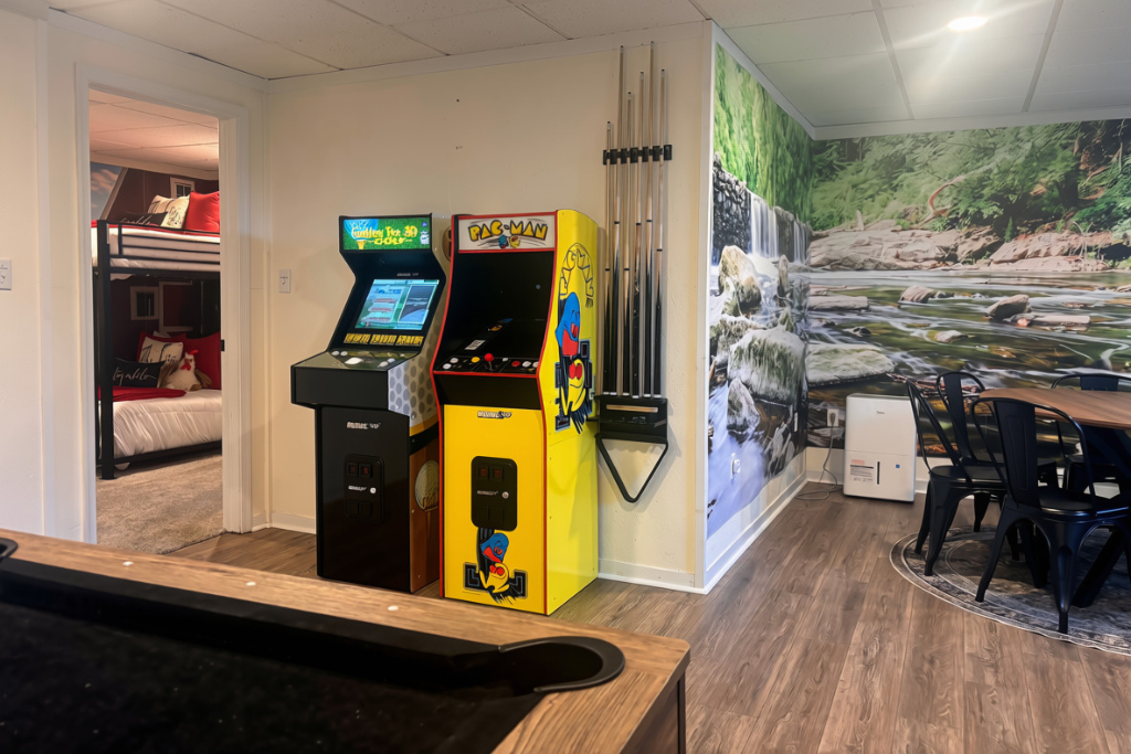 Pac-Man and Golden Tee, free play all stay. No quarters, no lines — just the two games everyone fights over, right outside the bunk room.