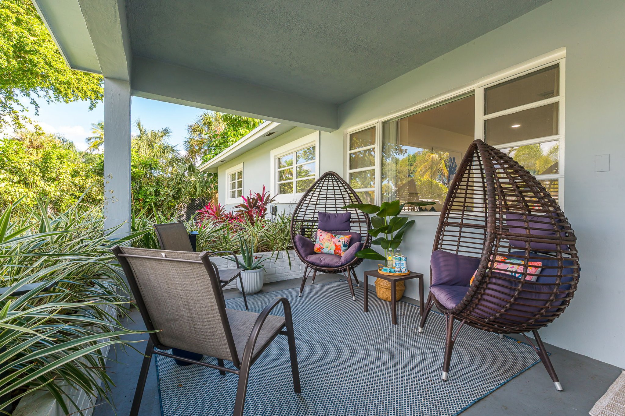 Chic front patio entry boasting designer egg chairs, colorful accents, and lush greenery, creating a serene, stylish first impression at Casa Palm Serenity.