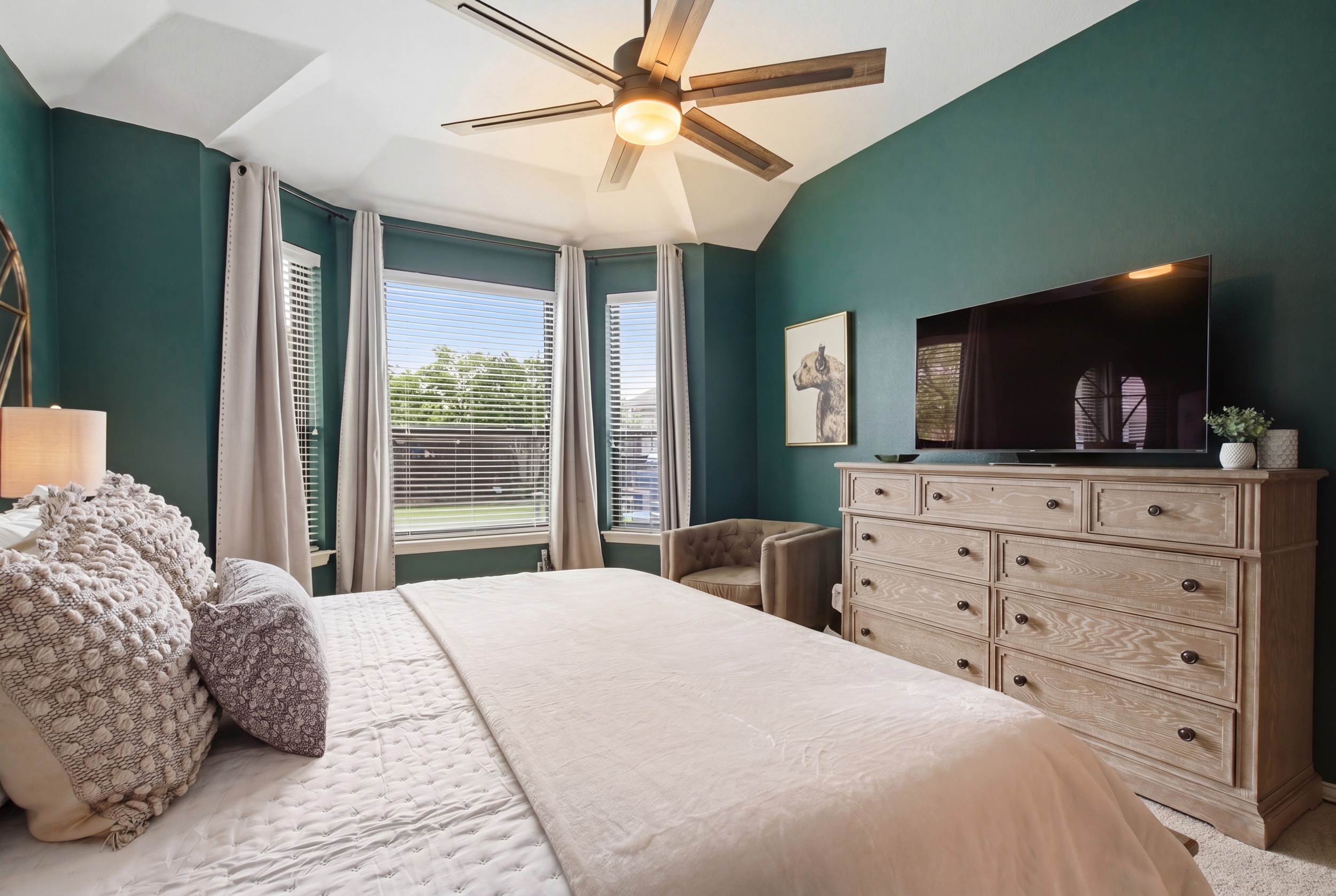 Master Bedroom with a King Bed, 65-inch Smart TV, ceiling fan, and large windows. Wake up rested and ready to explore North Texas.
