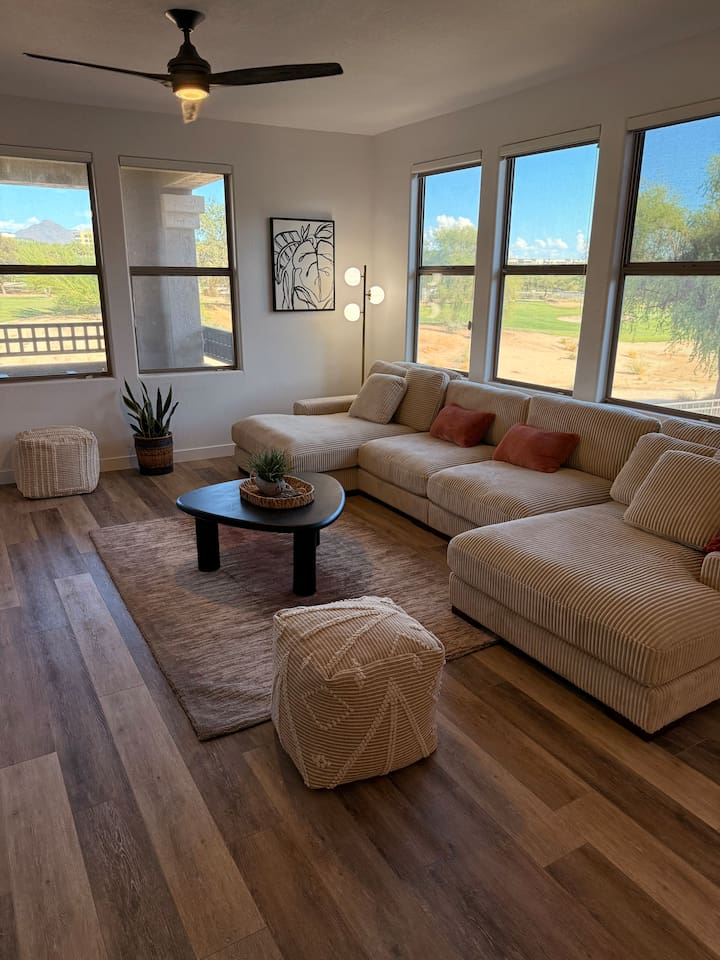 Living room with oversized sectional seating, wide windows, and open views of the desert landscaping outside.