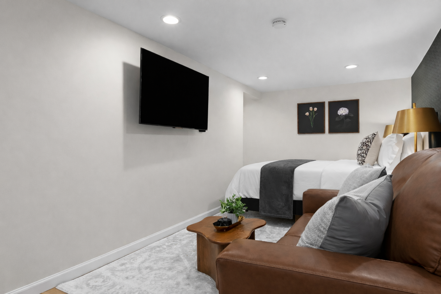 Comfortable studio living area featuring a plush bed, cozy seating, and wall-mounted TV—perfect for unwinding, streaming, and enjoying a relaxed stay.