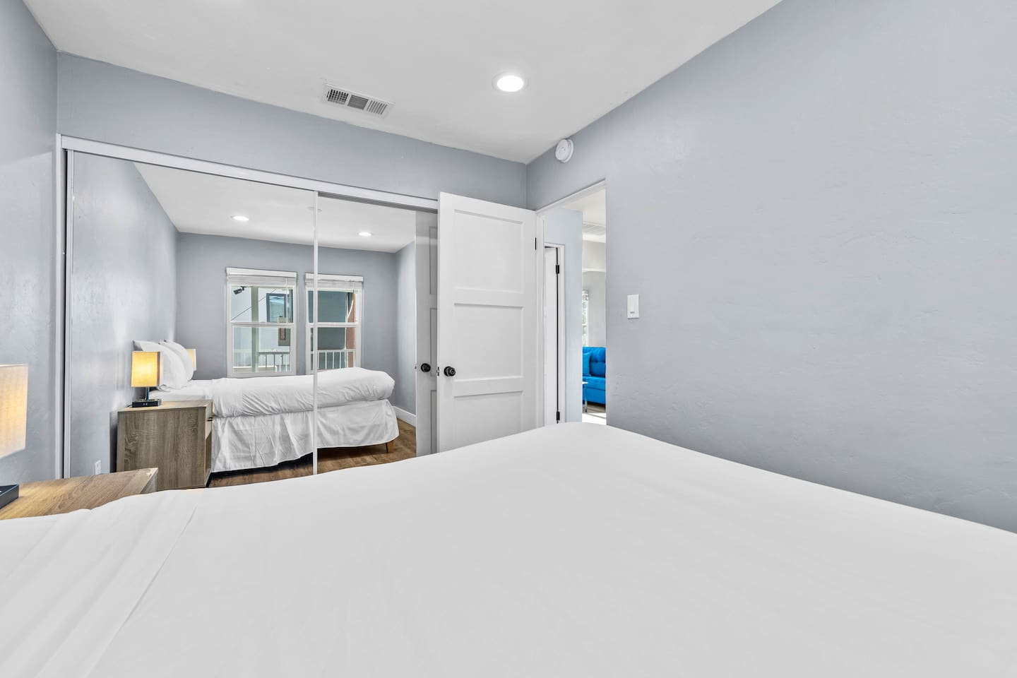 Cozy bedroom featuring a comfortable bed, an aesthetic lampshade for soft lighting, and a full-body mirror with an integrated clothes container. This setup combines style and functionality, creating a relaxing and organized space.