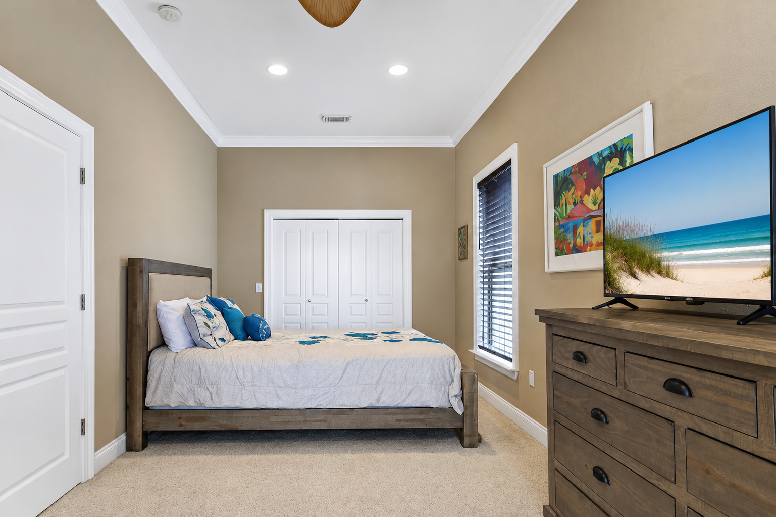 Guest bedroom with wood furnishings, smart TV, and coastal accents