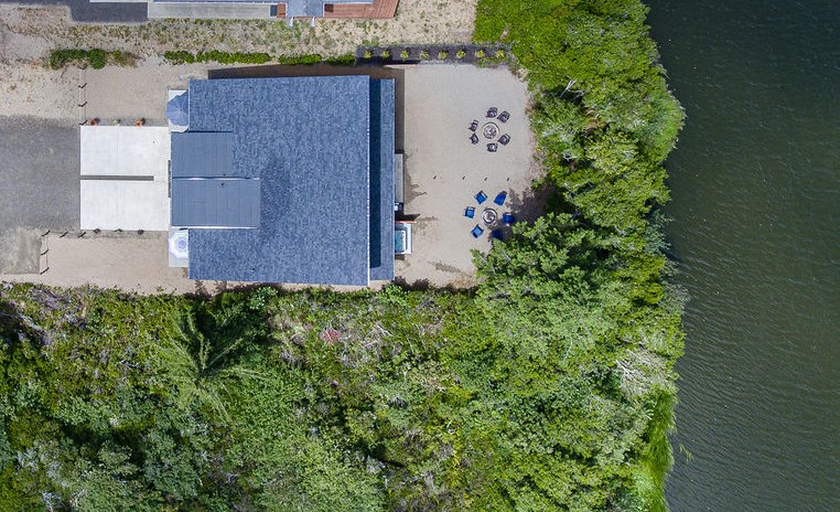 Straight overhead: the fire pit circle, cornhole, and canal edge — everything the backyard has to offer in one shot.