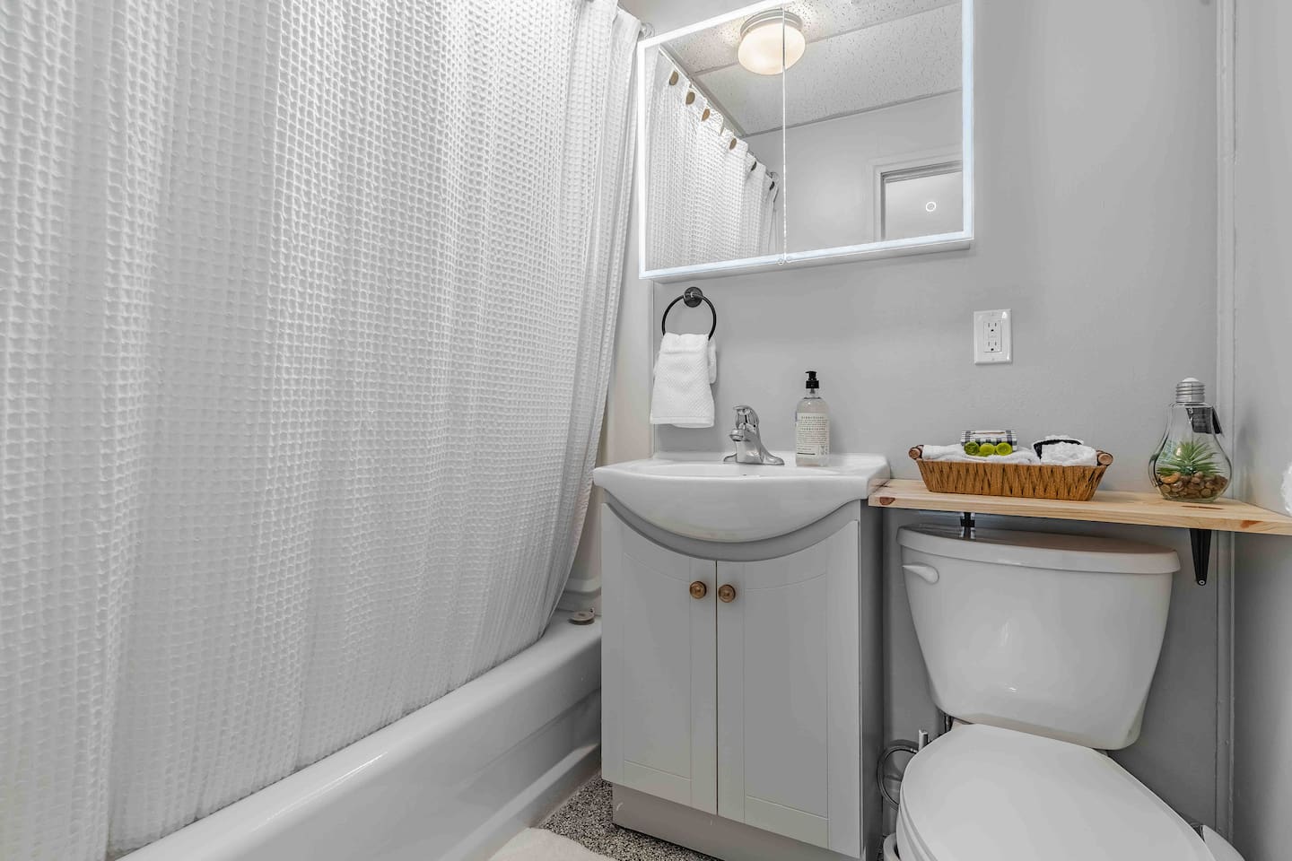 Basement full bathroom with tub/shower and lighted mirror.
