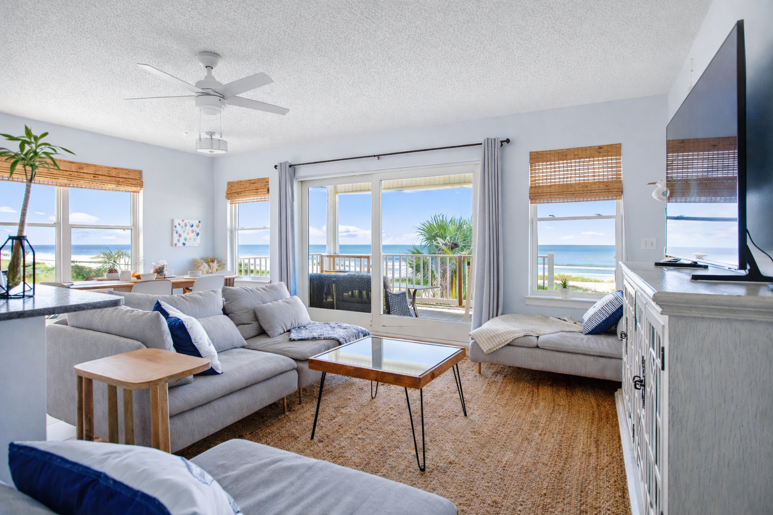 An open, light-filled living space with comfortable seating, dining area, and balcony access, where ocean views are always part of the room