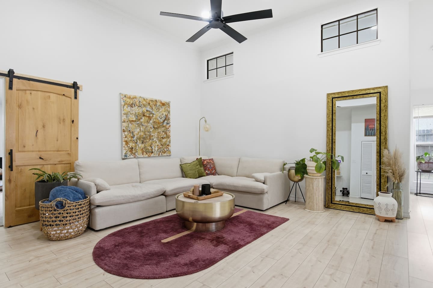 Bright open-concept living room with sectional sofa, Smart TV with streaming, ceiling fan, high ceilings, fast WiFi, and stylish seating perfect for relaxing or movie nights.