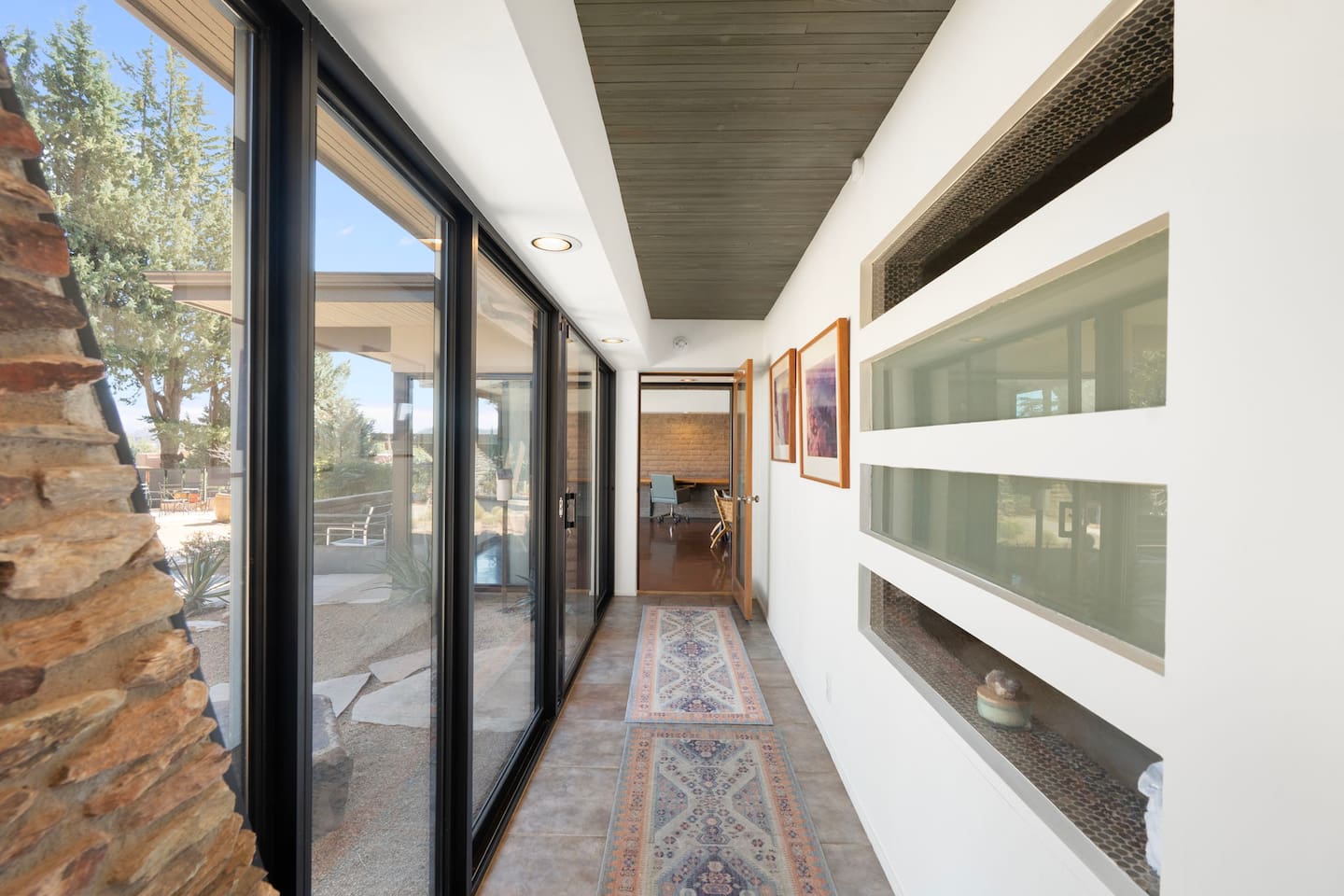 Bright hallway with sleek glass walls and seamless access to the outdoor patio.