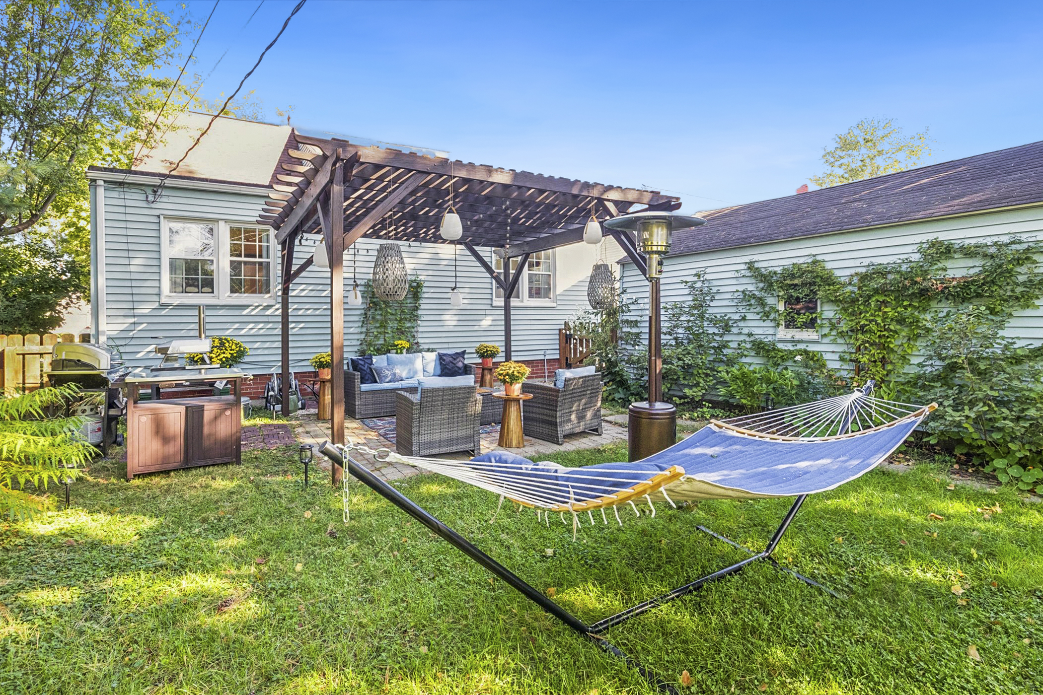 Unwind beneath the pergola—our South Bend guest retreat features a cushioned sofa, hammock, patio heater, and grill station. Cozy alfresco vibes and flavorful moments near Notre Dame.