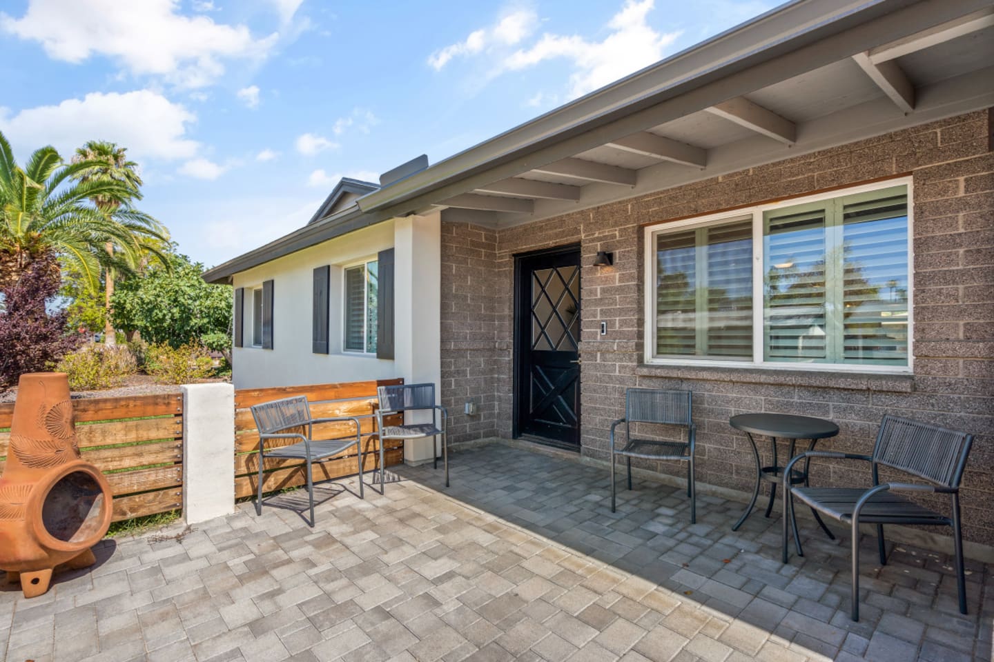 Front entrance with patio seating, paver walkway, and a welcoming outdoor spot for coffee or fresh air.