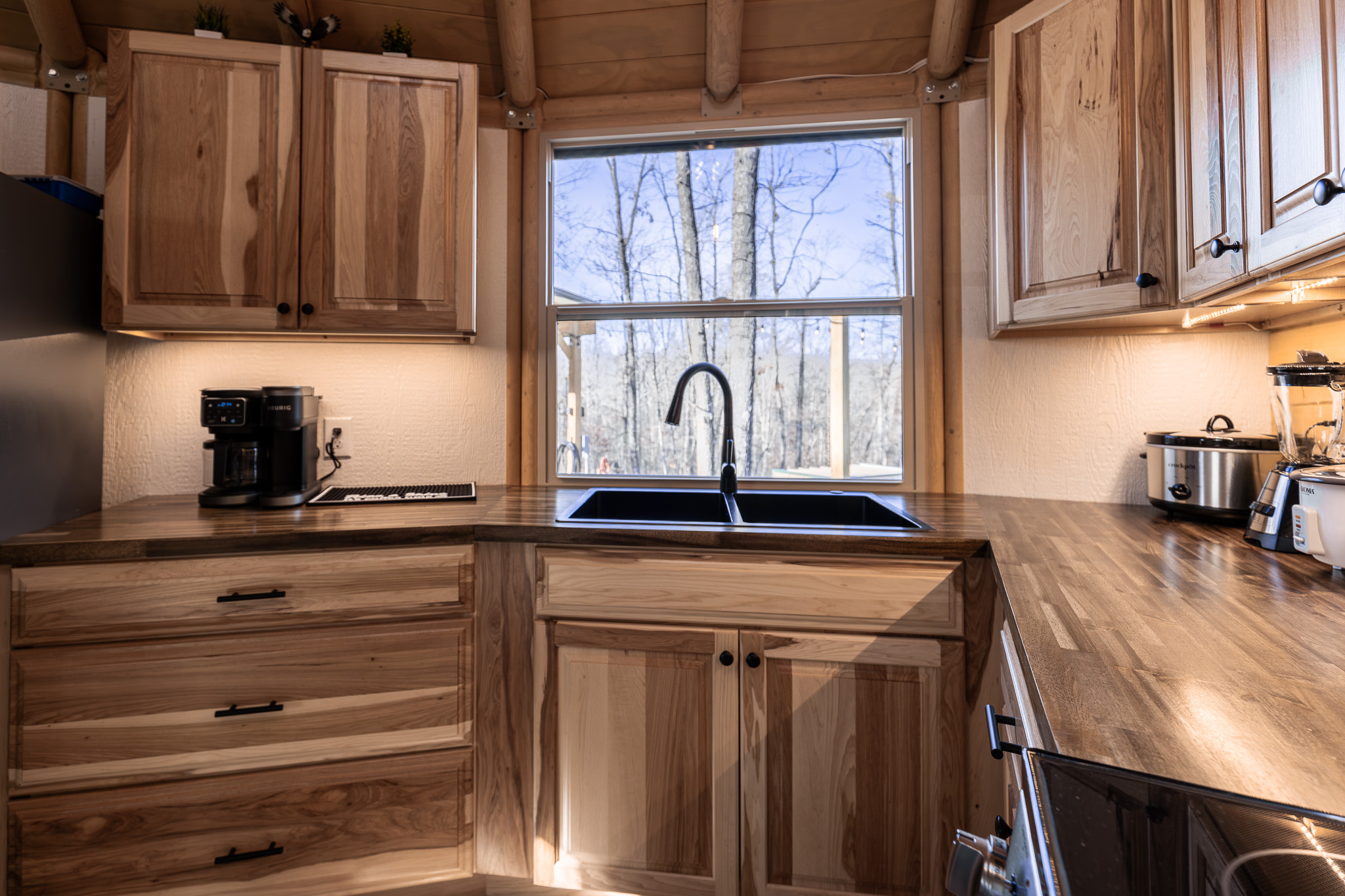 Enjoy generous counter space, a deep sink, and a peaceful forest view—perfect for slow mornings with coffee or preparing meals together in Eagle Retreat’s fully equipped kitchen.