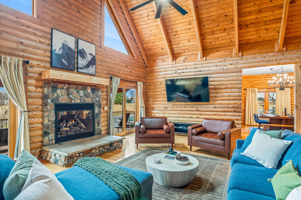 Spacious and inviting living area with a stone fireplace and large windows that bring in natural light and scenic views all day long.