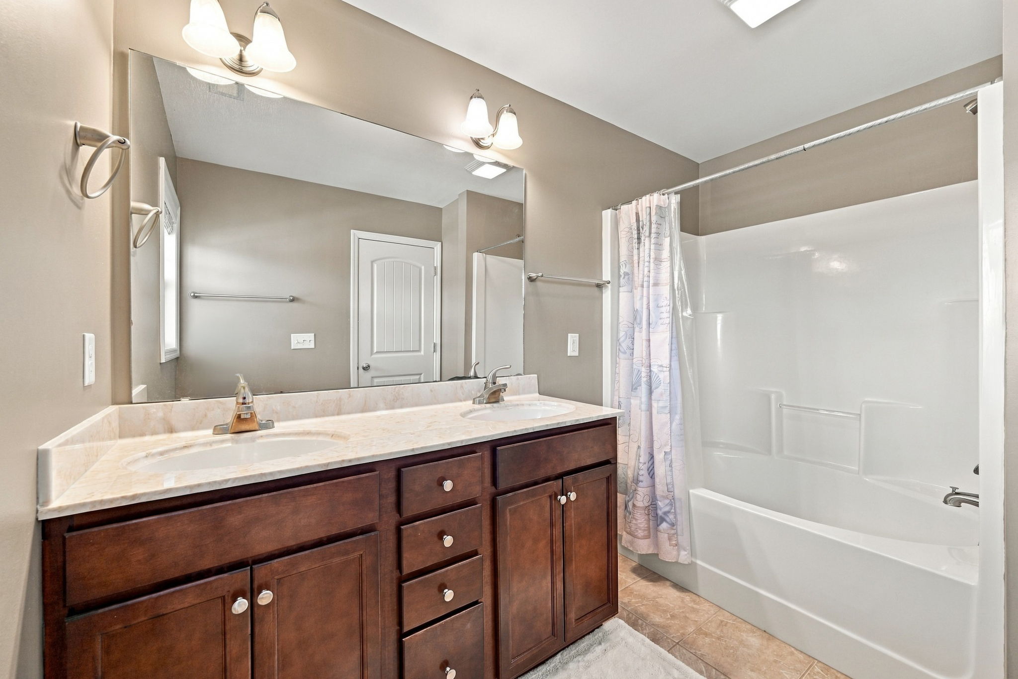 Spacious bathroom offering a double-sink vanity, generous counter space, and a shower-tub combination