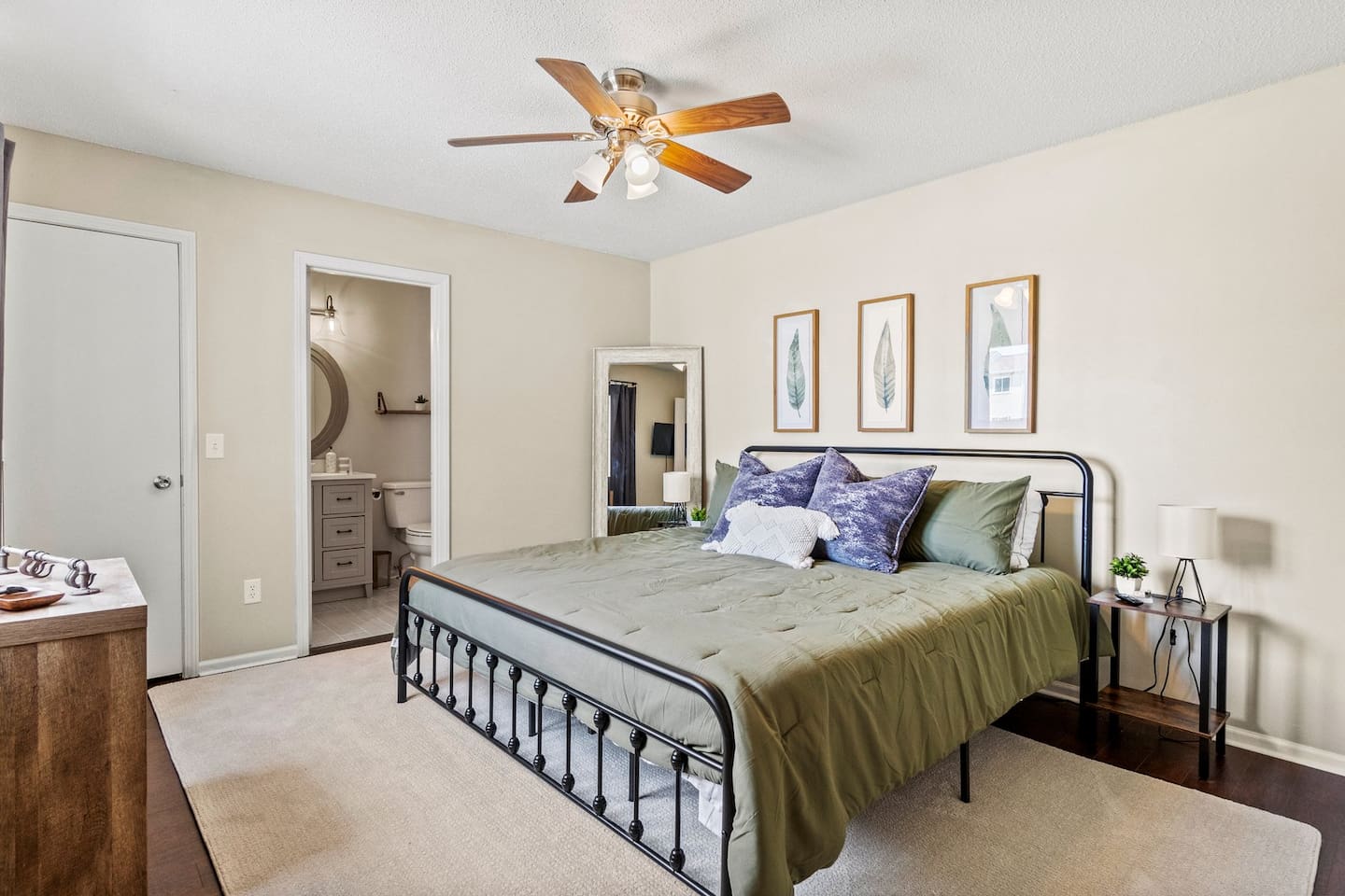 Unwind in this inviting primary bedroom featuring a plush king-size bed, calming earth-tone decor, and private ensuite bathroom access for added convenience.