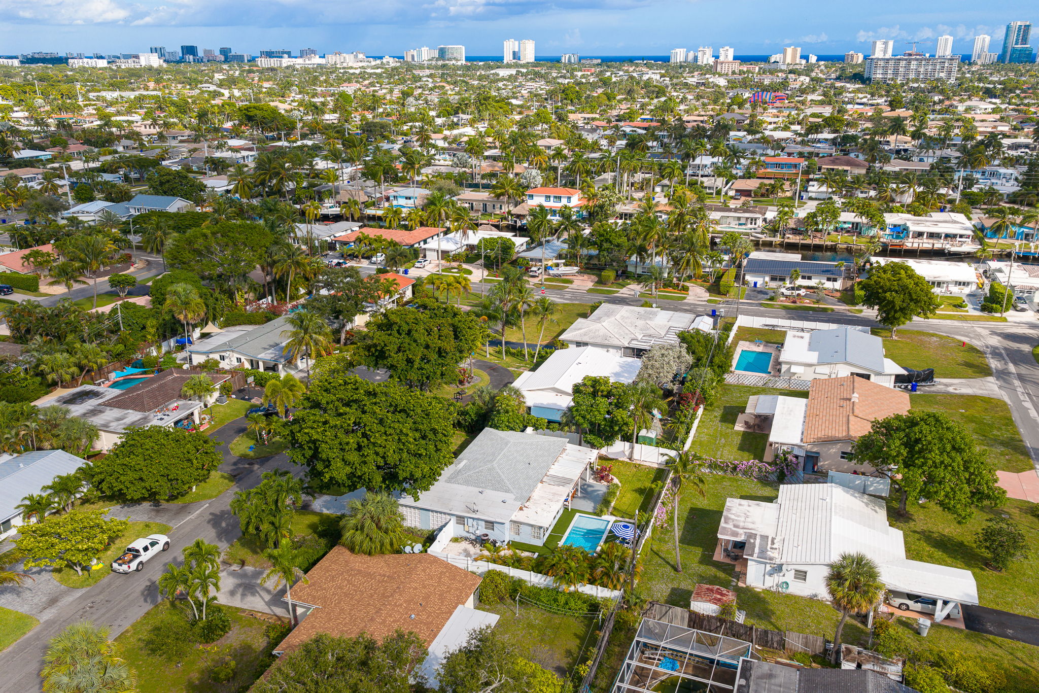 Soaring aerial perspectives highlight the home’s tranquil Pompano Beach neighborhood, private backyard oasis, covered carport, and extended driveway with space for 3 cars.
