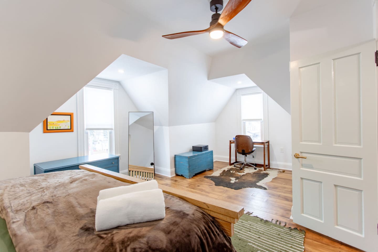 A spacious bedroom featuring a comfortable bed and a dedicated workspace, with a sleek desk and chair, offering a perfect blend of relaxation and productivity.