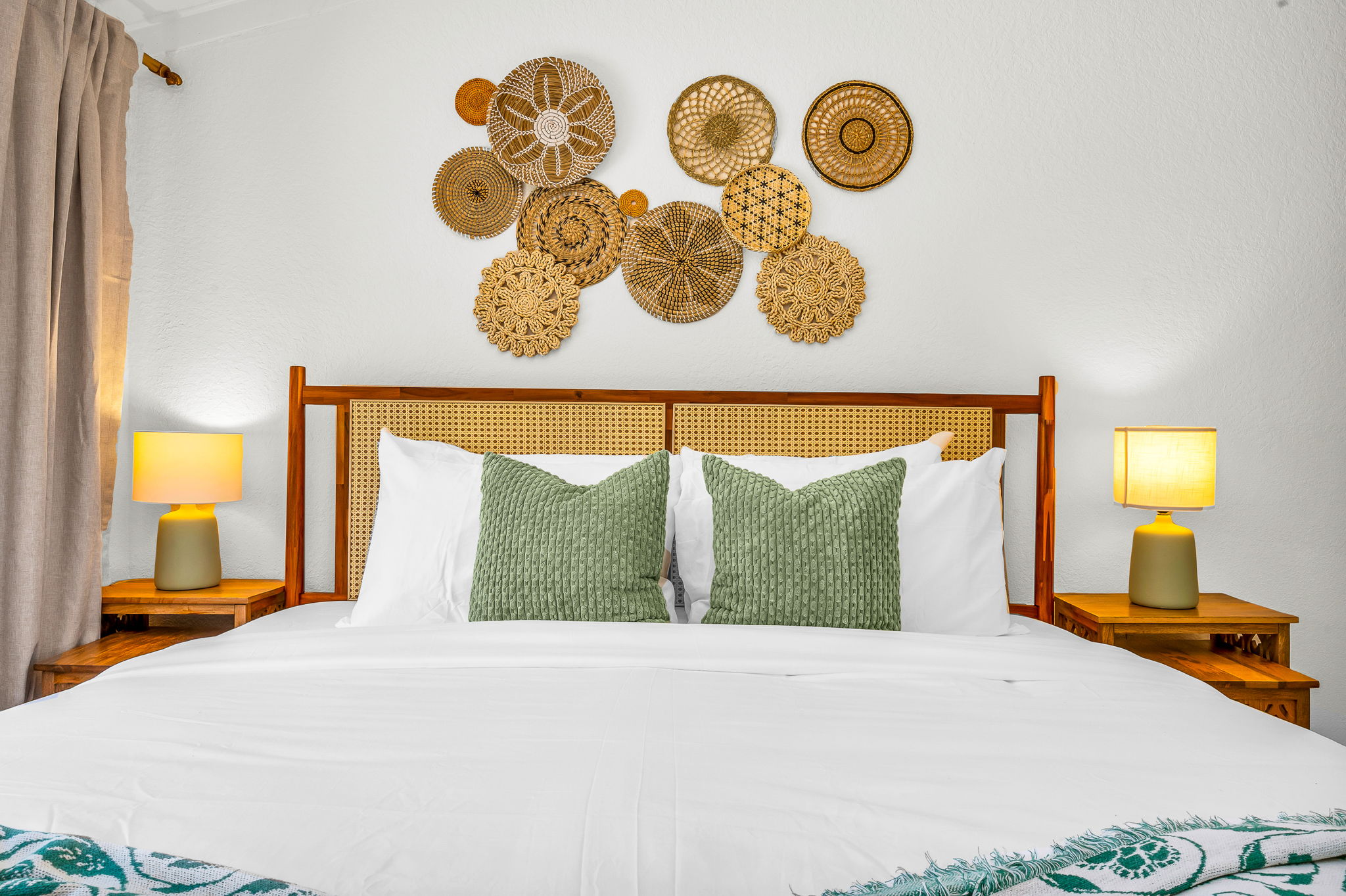 Serene ensuite primary king suite featuring a plush bed with luxury linens, vaulted ceilings with exposed beams, and elegant coastal décor. Includes a spacious walk-in closet with washer and dryer for added convenience and comfort.