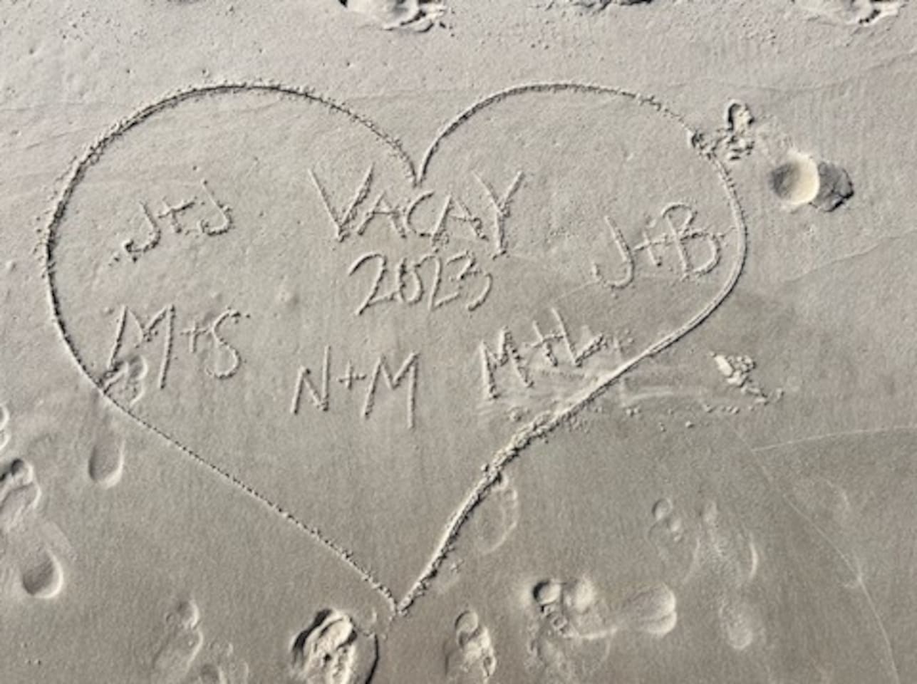 Beach vibes: Heart in sand marking 2023 love, memories, and connections.