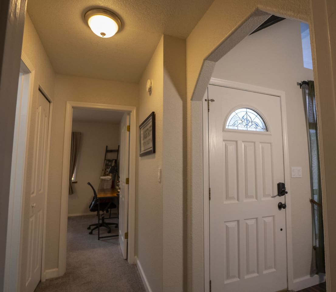 Entry hallway with access to rooms, arched doorway, and a view toward the bedroom with workspace area.