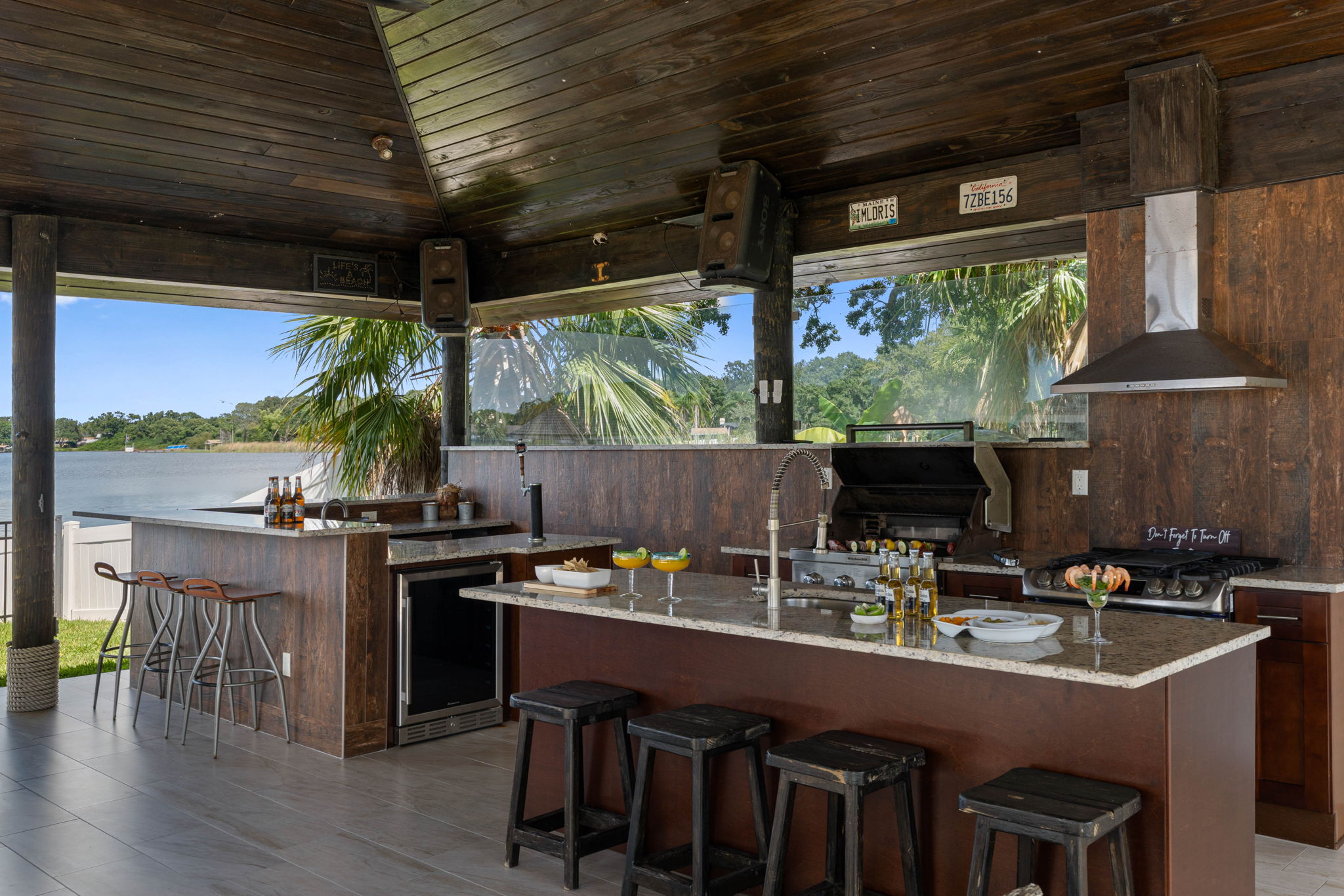 This expansive covered patio offers a full kitchen, bar seating, hanging chairs, and lounge areas, all with stunning waterfront views.