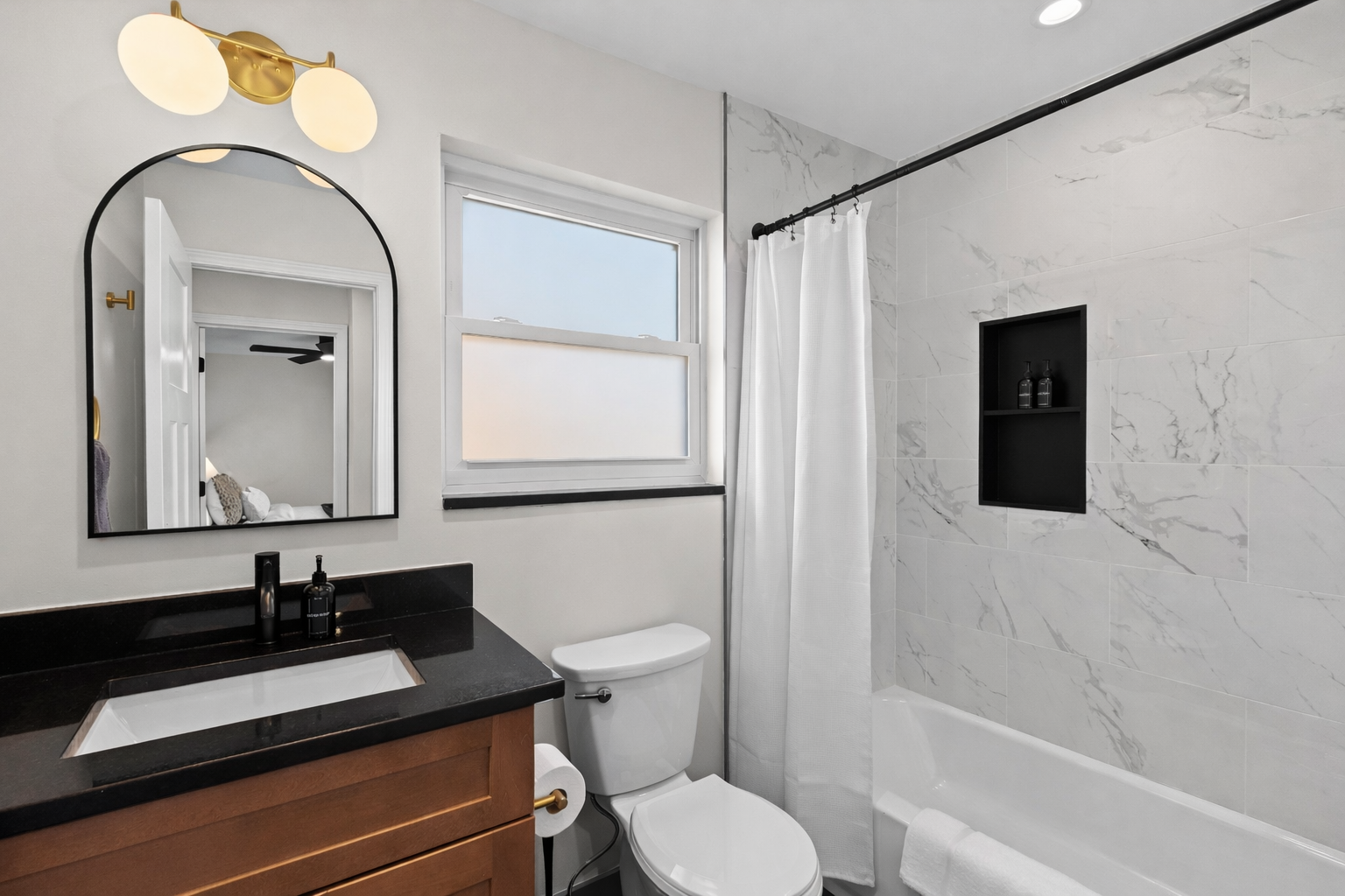 Fresh, modern bathroom with sleek vanity, bright window, and tiled tub-shower—clean, stylish, and perfect for a refreshing start or relaxing unwind.