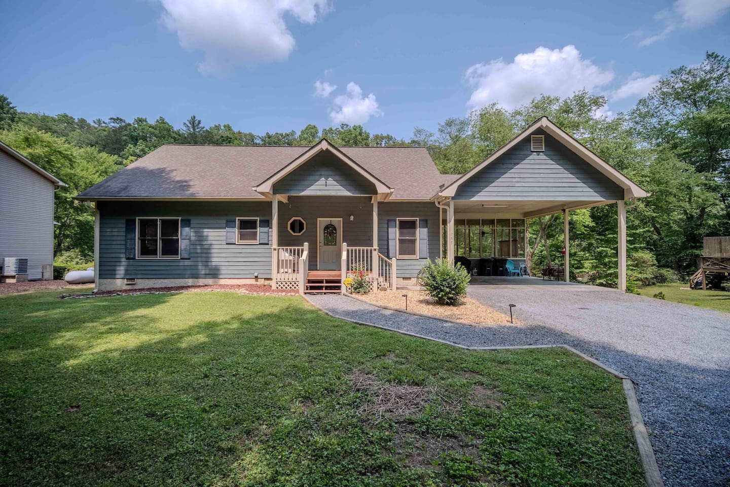 A charming riverfront home with a welcoming front porch, covered carport, and a spacious driveway. This serene setting is perfect for enjoying the peace and beauty of nature.
