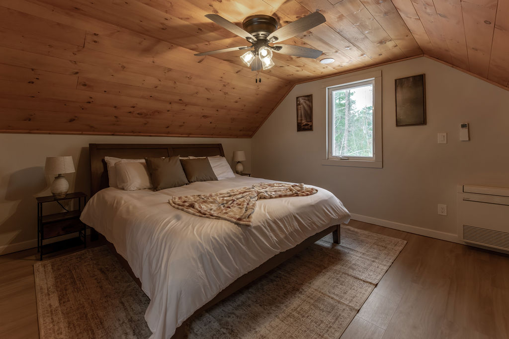 Master bedroom with a king size mattress, walk in closet, ensuite bathroom, and a window to bring the Adirondack outdoors inside!
