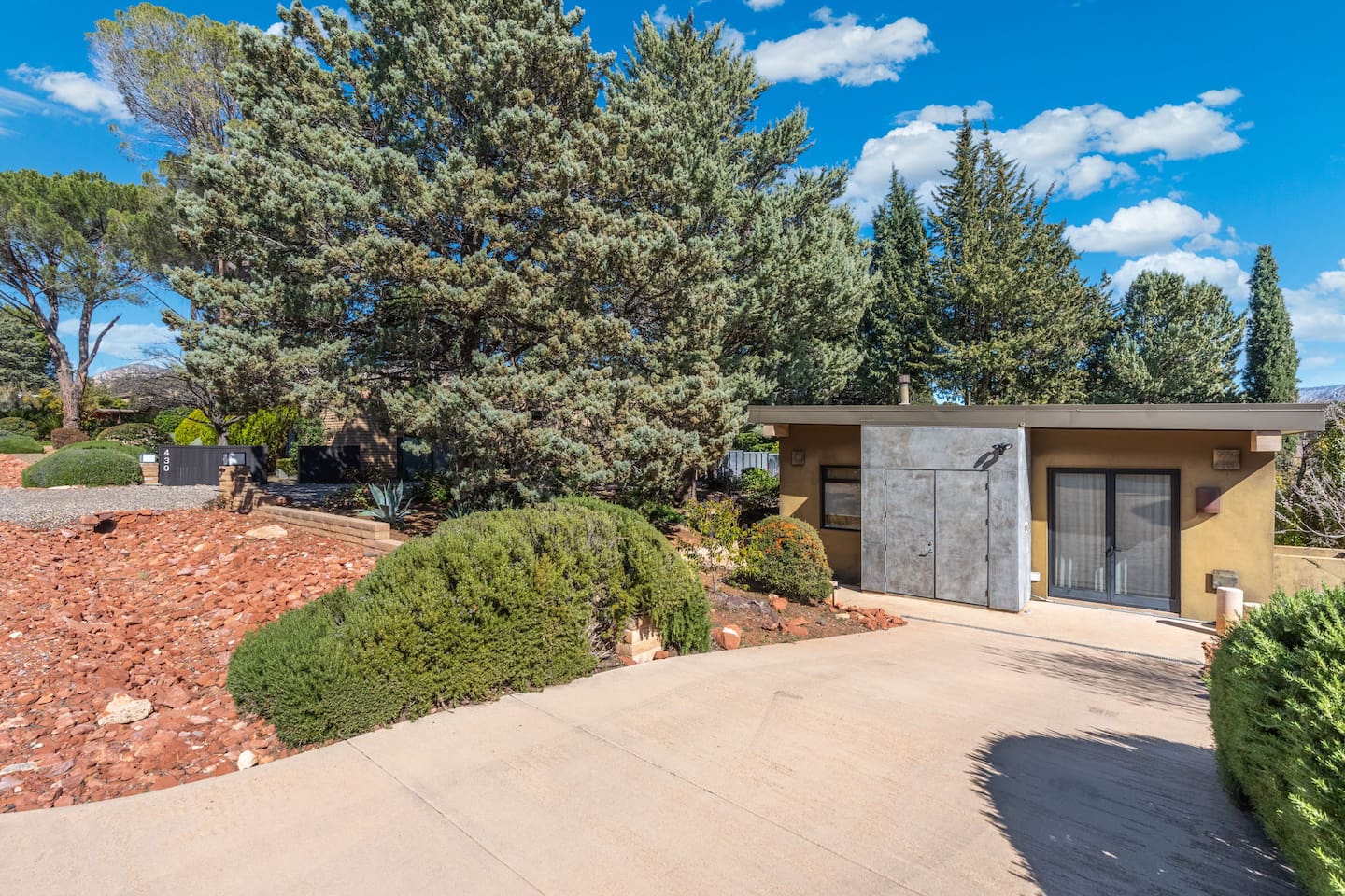 Bright daytime exterior showcasing the modern façade, clean lines, and beautifully maintained desert landscaping.