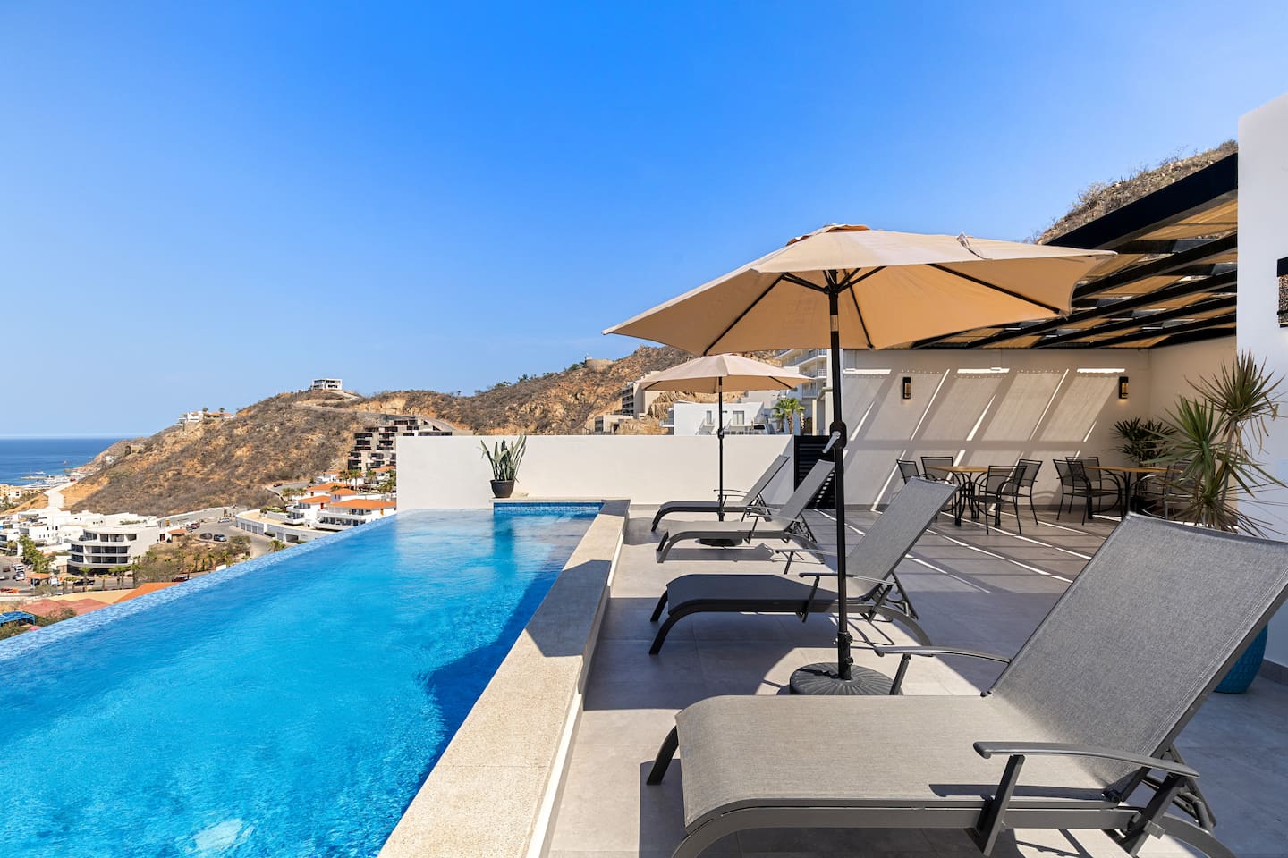 Featuring plush lounge chairs, a shaded cabana, and a outdoor dining tables, it’s perfect for lounging and socializing in this Cabo oasis.