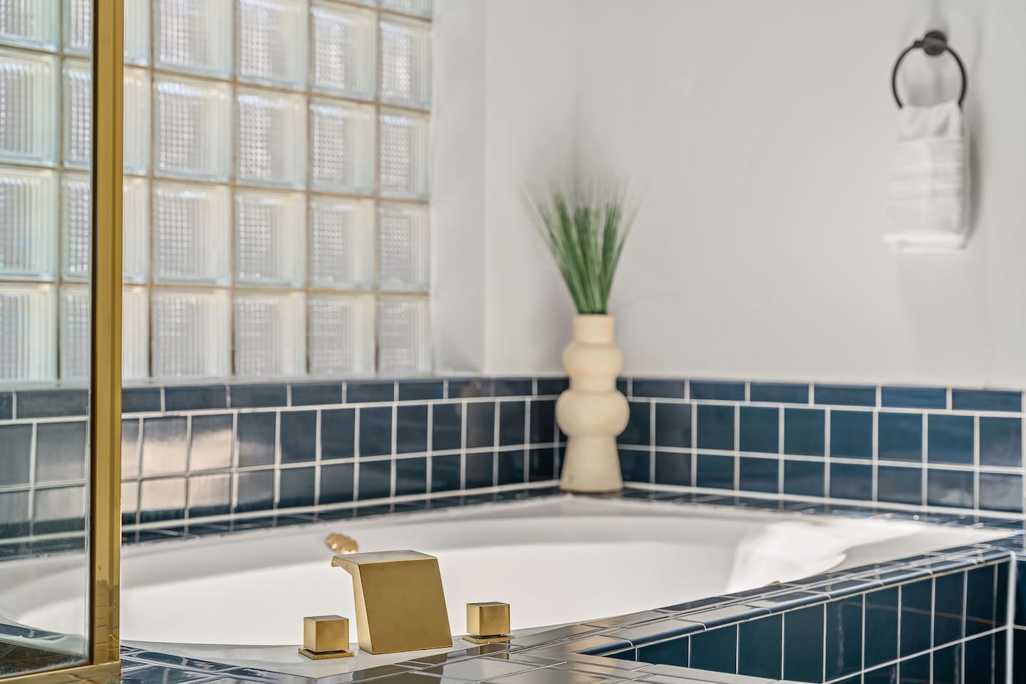 Unwind in this stylish soaking tub with deep navy tile and gold finishes.