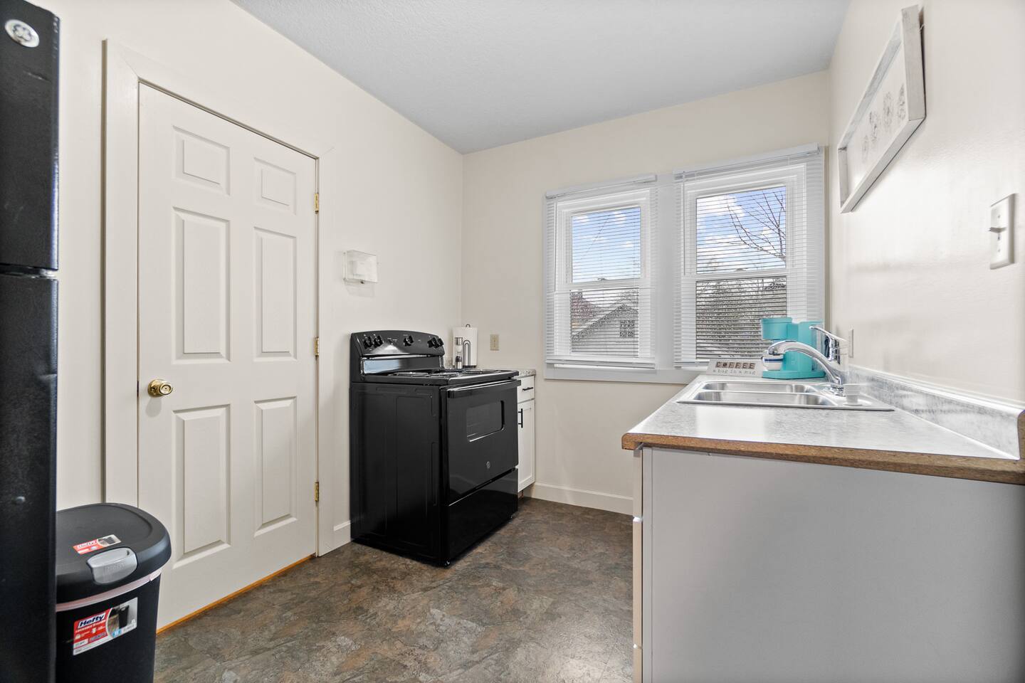 Modern full kitchen featuring a sleek sink with faucet, stylish cabinets, elegant granite countertops, a stove, and a window that lets in natural light—designed for both functionality and contemporary style, creating an inviting cooking space