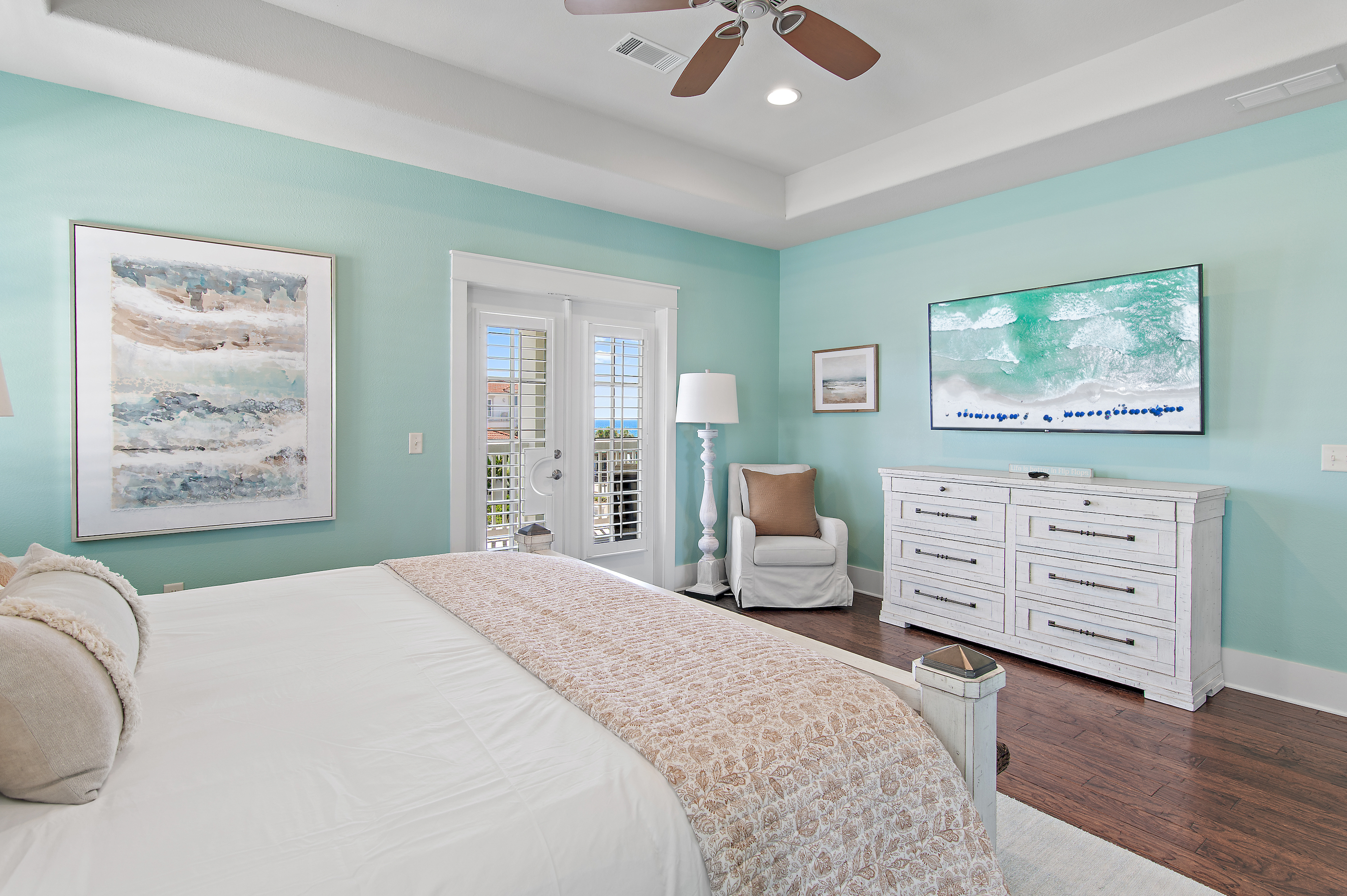 Relax in this spacious coastal bedroom, featuring a comfortable king bed, soft beach inspired décor, and plenty of natural light.