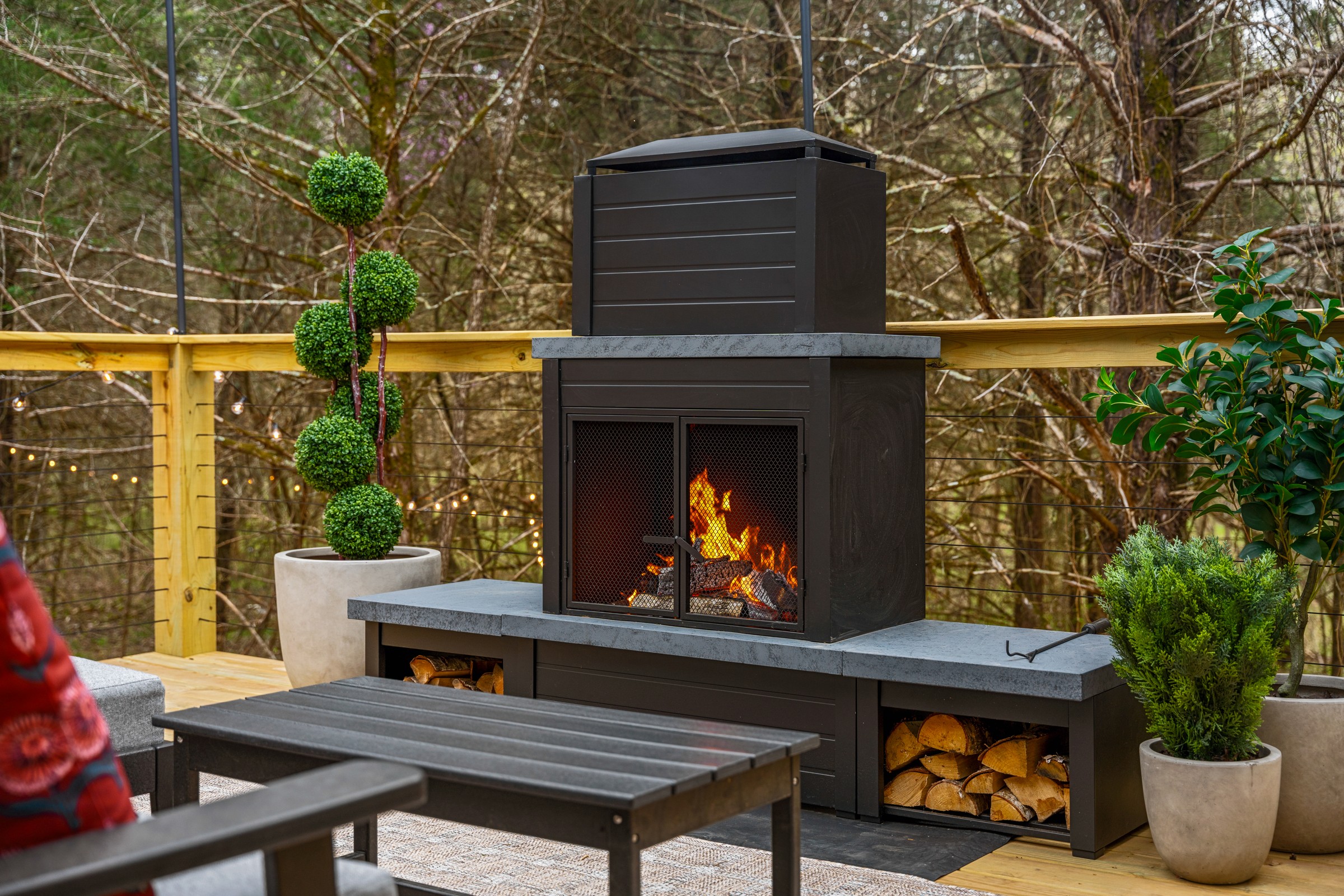 Outdoor wood fireplace with stacked firewood on the deck. Firewood is provided, so you can light it up on arrival.