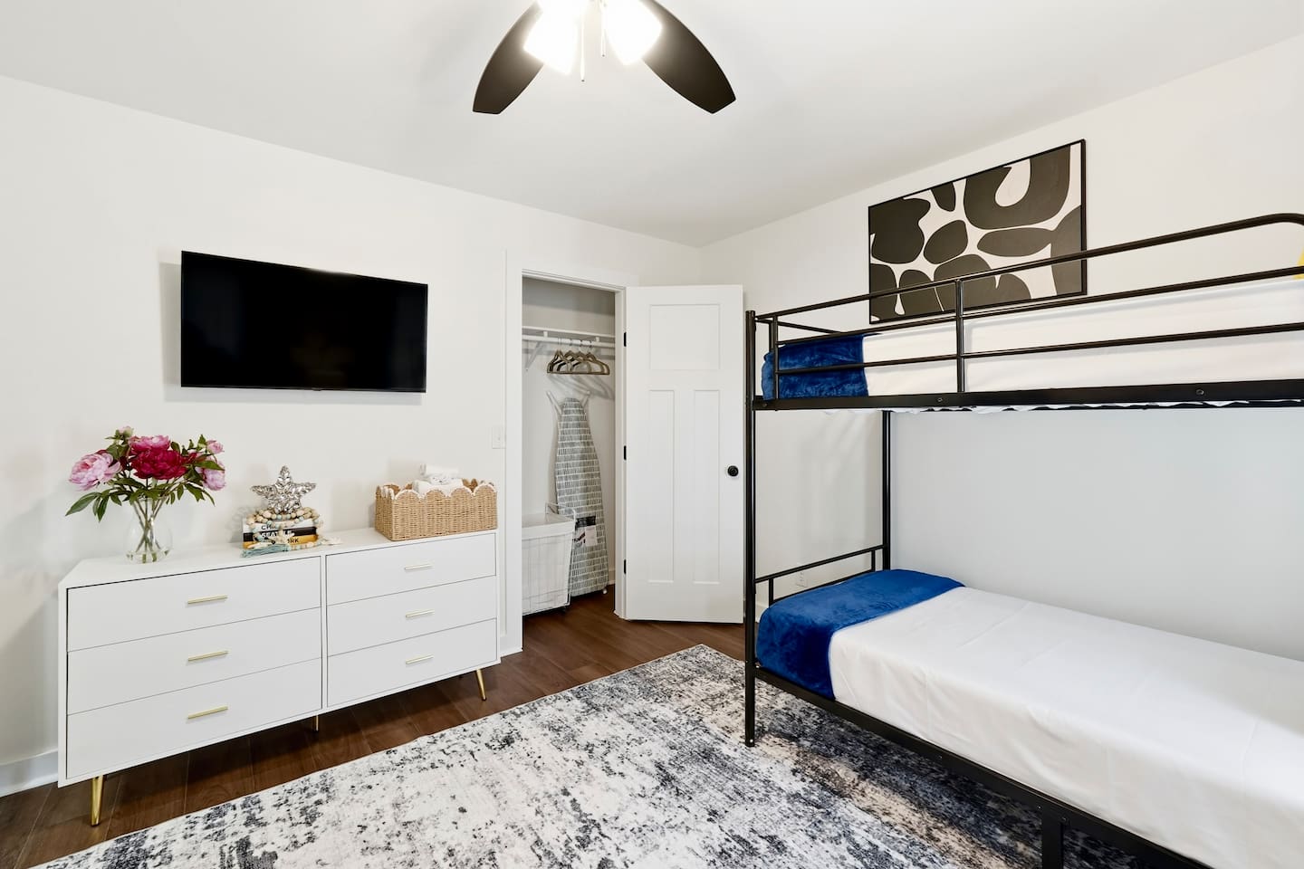 On the second level, you’ll find a cozy bedroom featuring two bunk beds, each equipped with comfortable blankets and a Roku-powered TV. This welcoming room is the first one you’ll encounter as you walk up the stairs.
