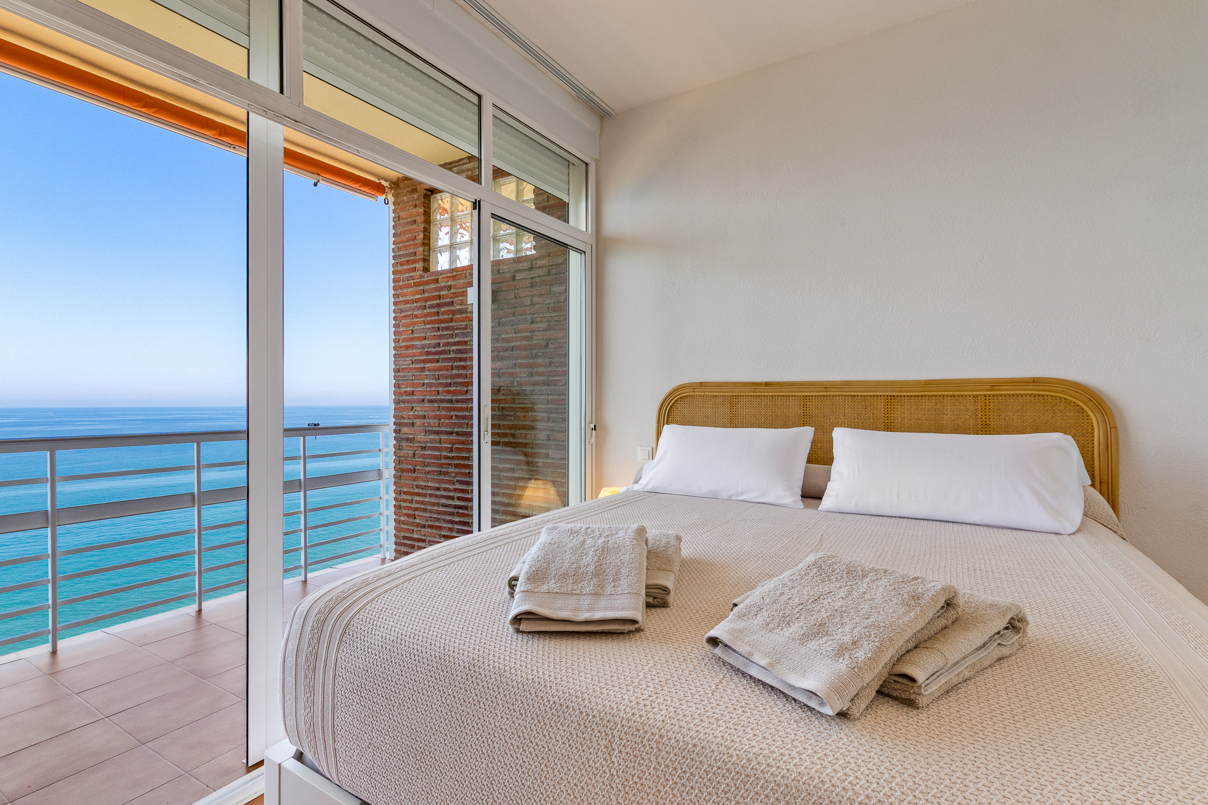Bedroom opening onto a balcony with panoramic Mediterranean views.