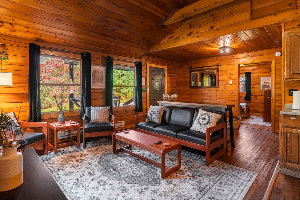Cozy up in a warm wood-paneled cabin with modern comforts, plush seating, and scenic views just outside your window