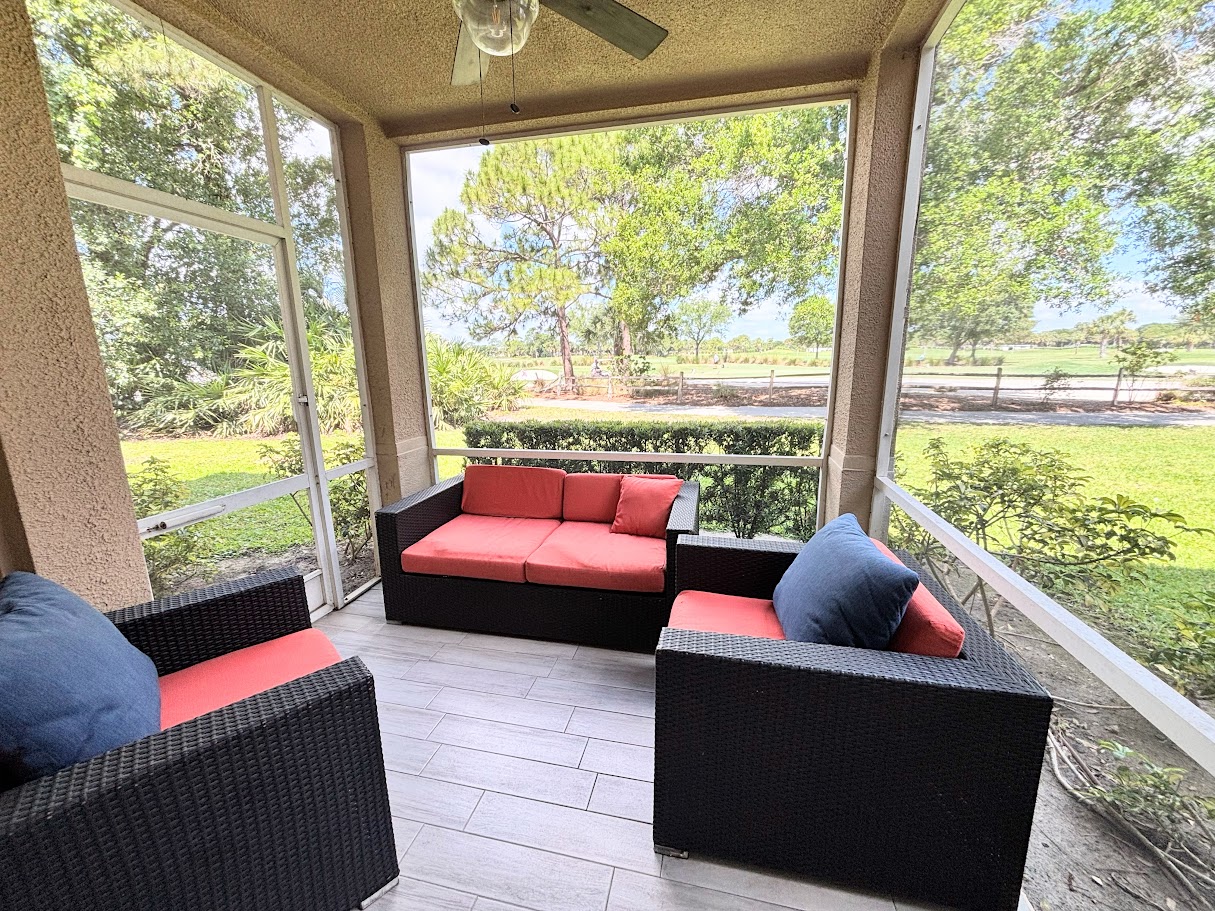 Private screened patio with comfortable outdoor seating and relaxing views of the surrounding green space.