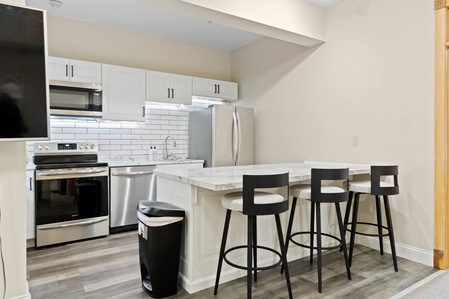 Modern kitchen featuring a sleek countertop with seating for three, complemented by elegant white interiors for a clean and stylish look.
