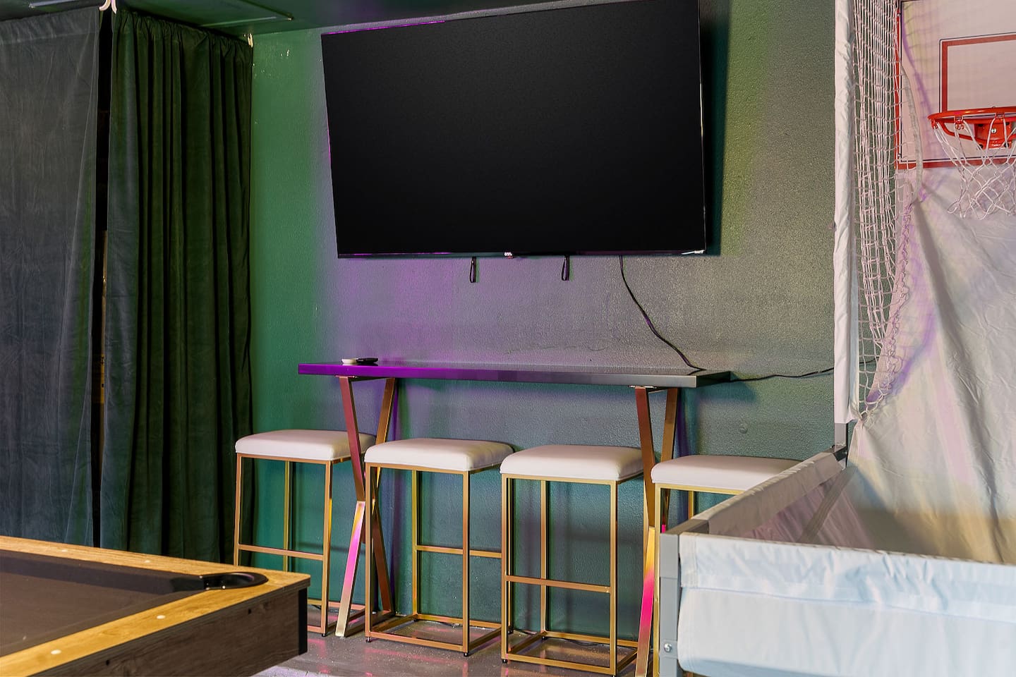 Enjoy this modern entertainment corner equipped with a large TV, a sleek high table, and comfortable bar stools.