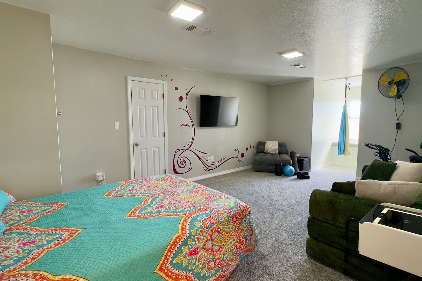 A well-lit bedroom/living area with recessed lighting and soft gray carpeting creates a welcoming atmosphere.