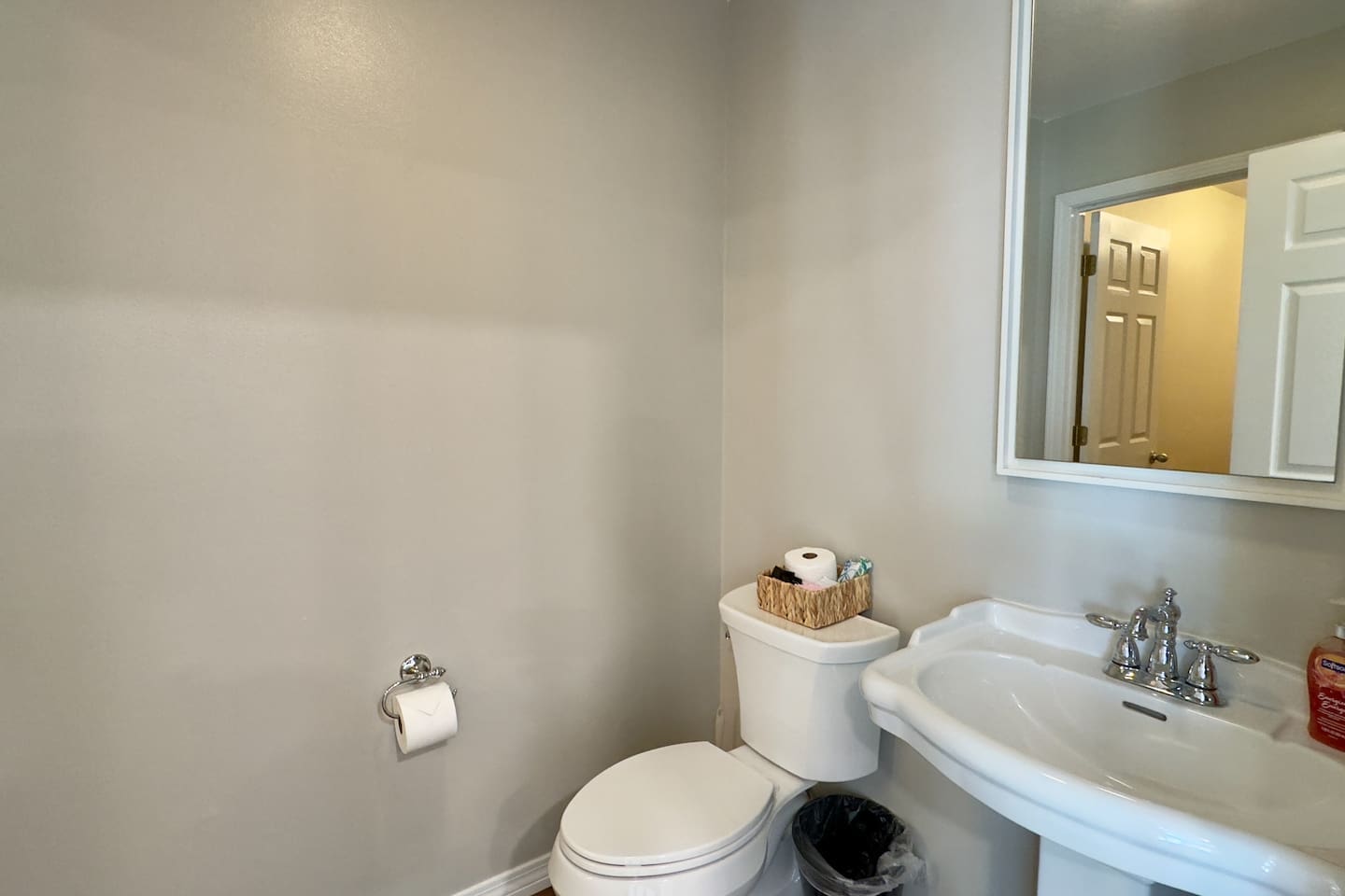 A pedestal sink with chrome fixtures and a rectangular mirror creates a simple, stylish centerpiece.