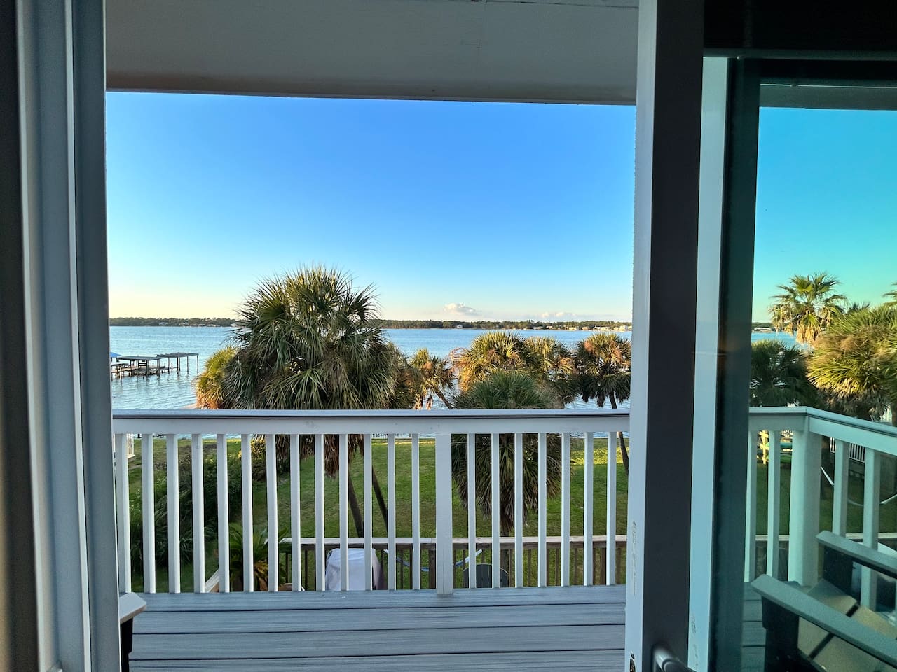 Tranquil balcony view with lush palm trees and sparkling waterfront serenity.