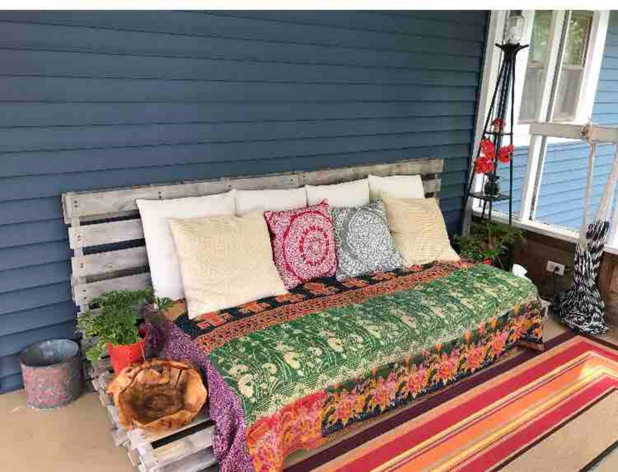 Bohemian style screened in porch with twin bed/couch, dining table, and hammock. Great for lounging during warm weather!