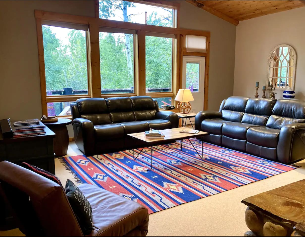 Main floor living room - Great views and a deck nestled in the aspen trees! Comfy couches with four reclining seats, large TV, desk, and open floor plan to kitchen and dining.