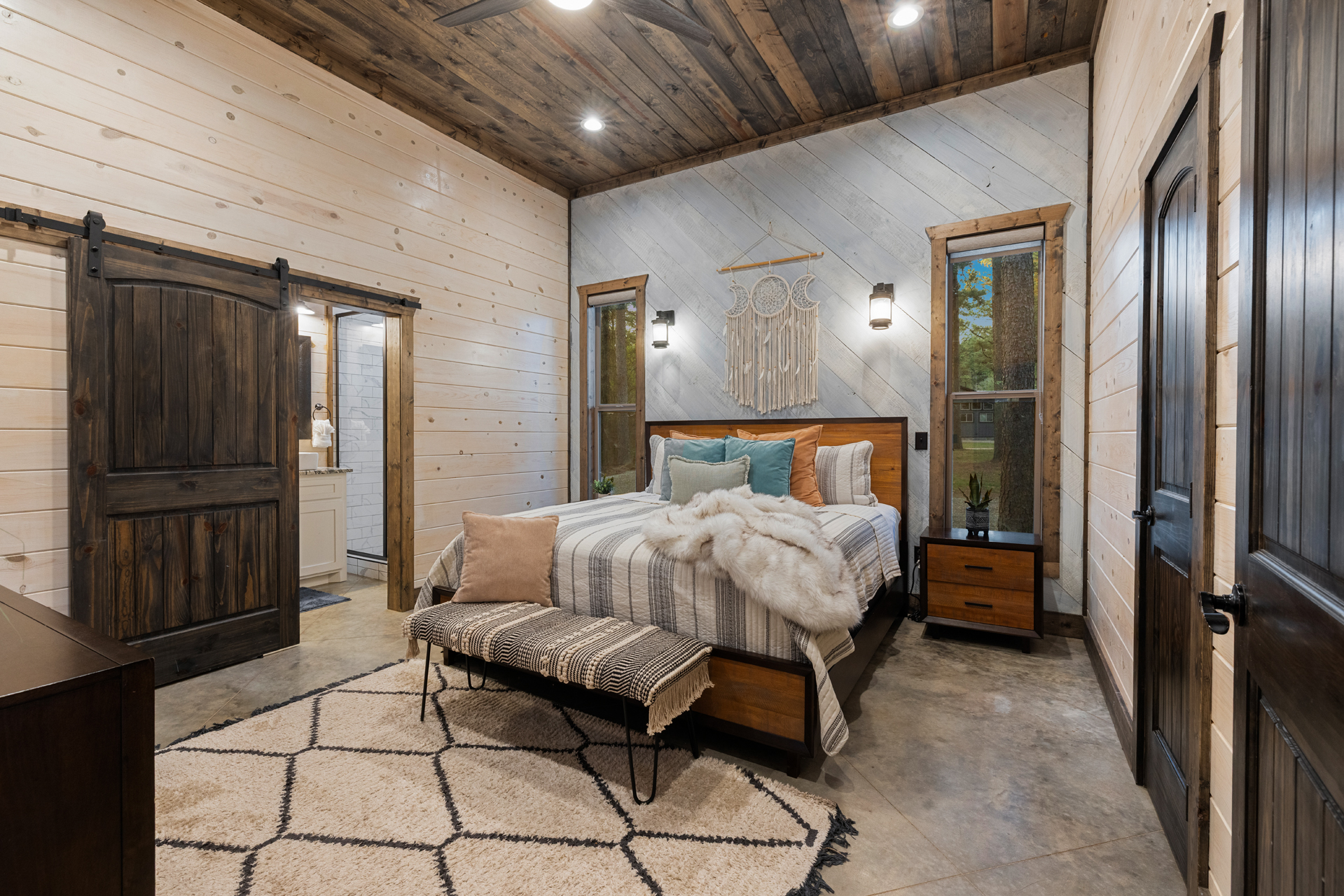 Soft bedding, warm wood accents, and gentle light set the tone for deep rest. Wake to calm forest views and a slow, unhurried morning in this King bedroom with attached bathroom.