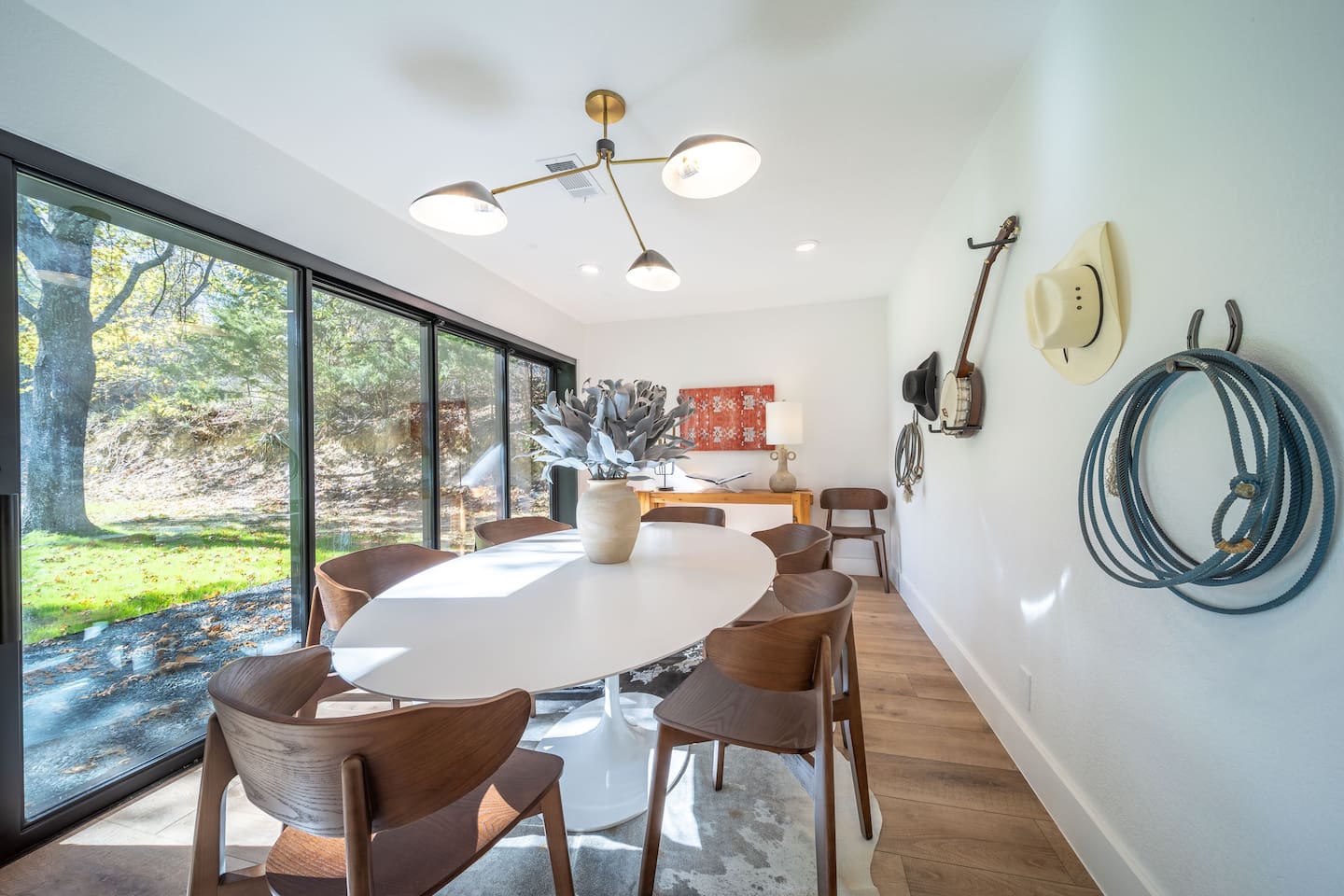 Dining area with a modern chandelier, sculptural centerpiece, and seating arranged for comfortable group dining. Clean lines and warm finishes give the space a refined, welcoming feel.