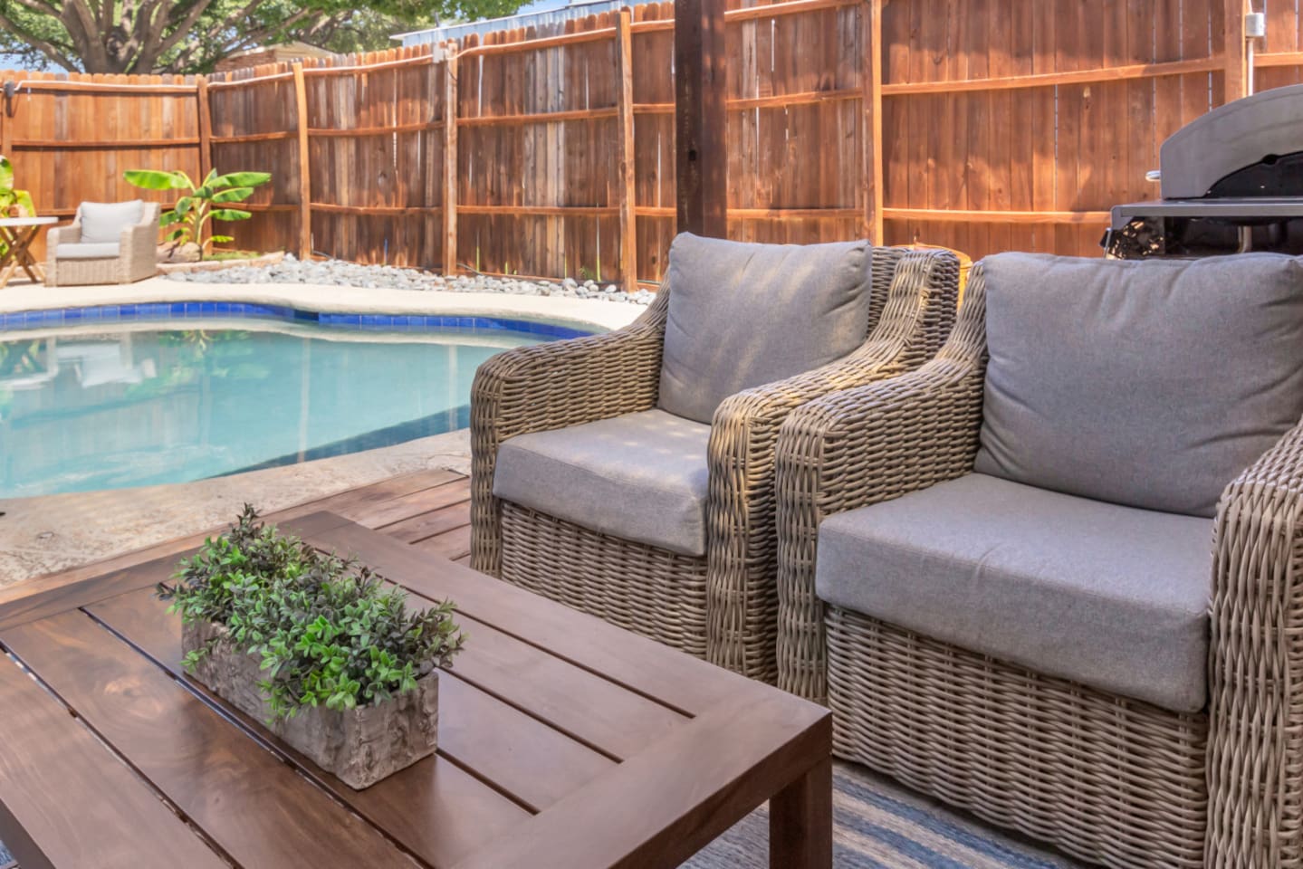 Zoomed in view of the covered patio's sitting area, coffee table, and poolside vibes. 
